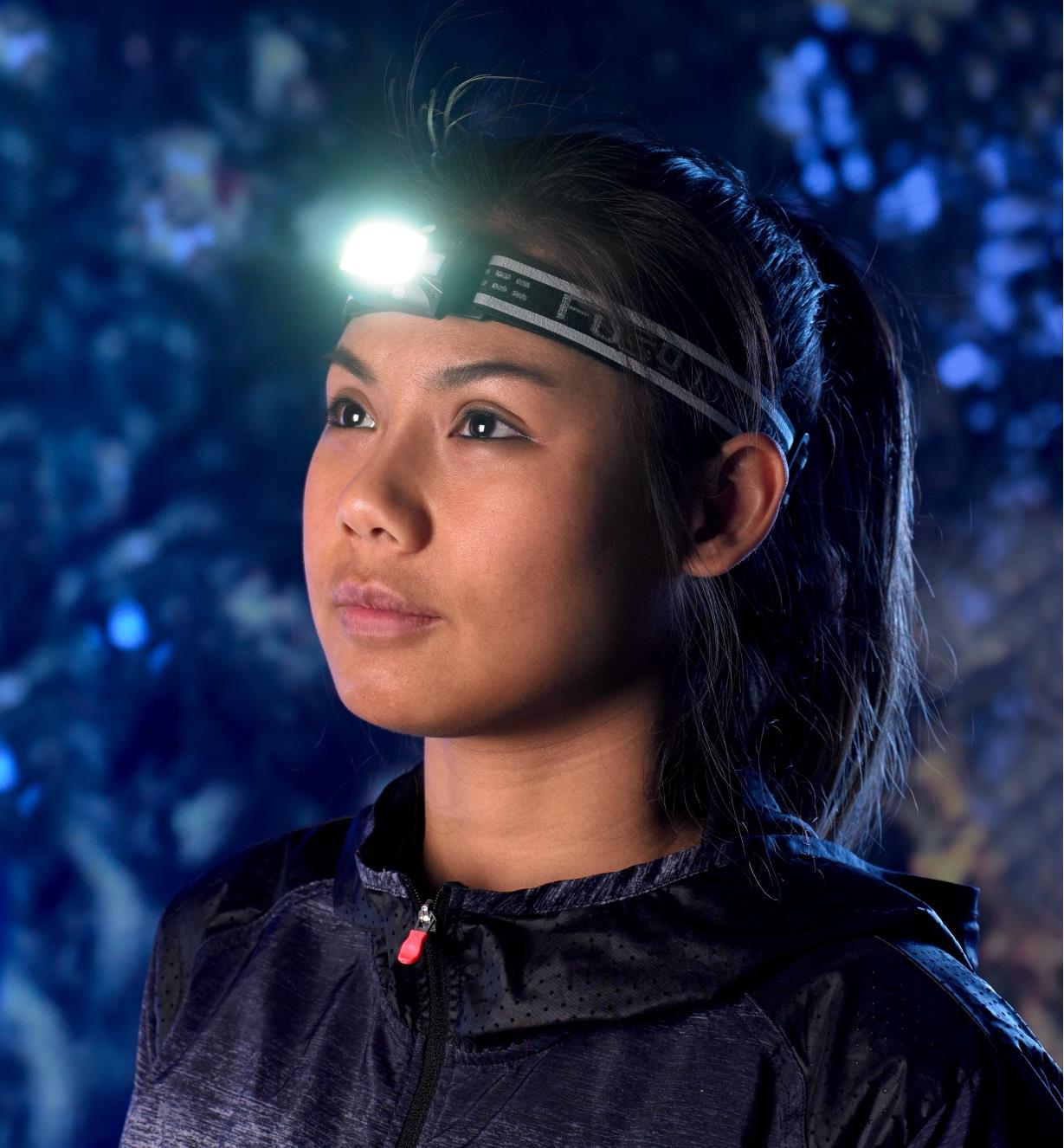 Attached to a headband, the multi-function LED headlamp is positioned on the forehead