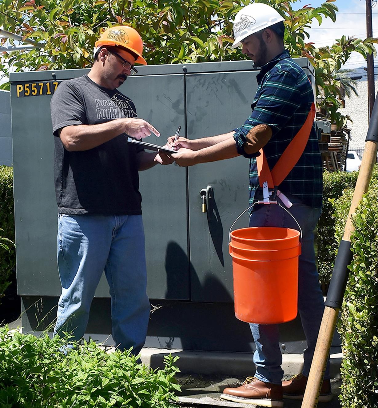 A man uses a Bucket Buddy Sash to hold a pail off the ground, freeing his hands to fill out forms