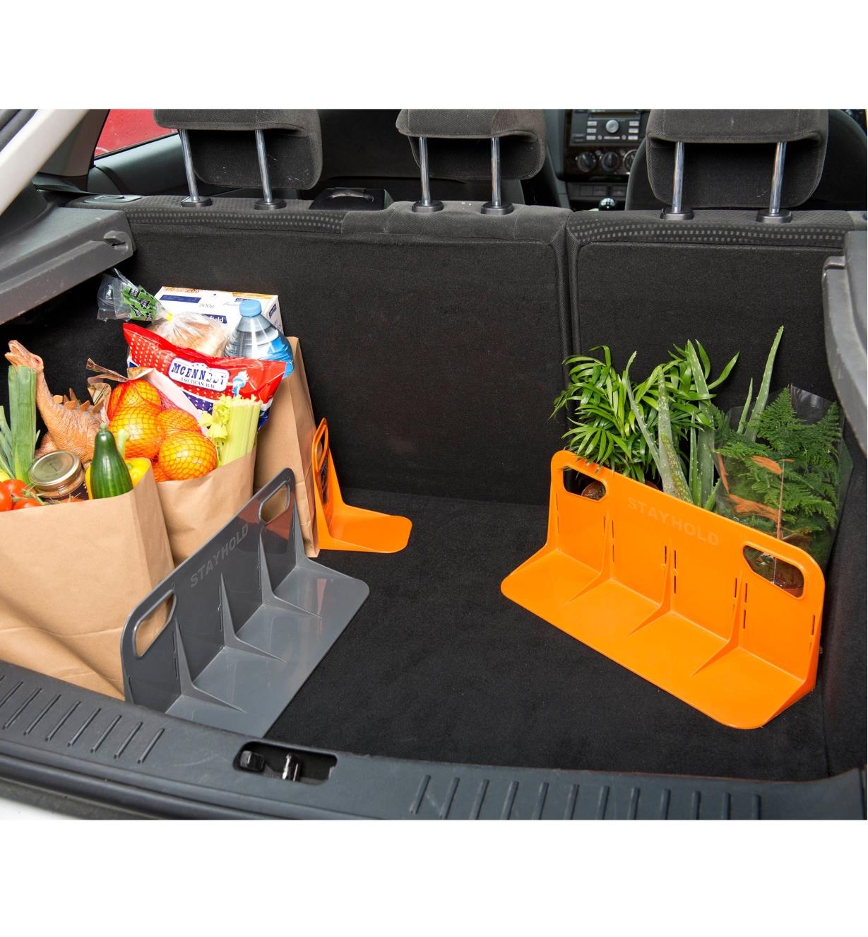 Three brackets supporting grocery bags and plants in a vehicle's cargo area