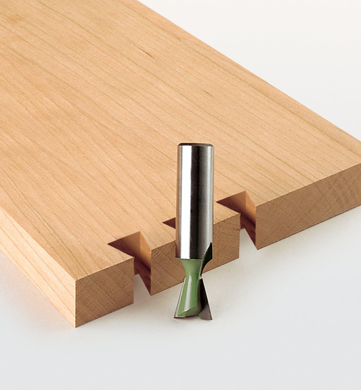 Dovetail bit next to a board with dovetail joints cut into it