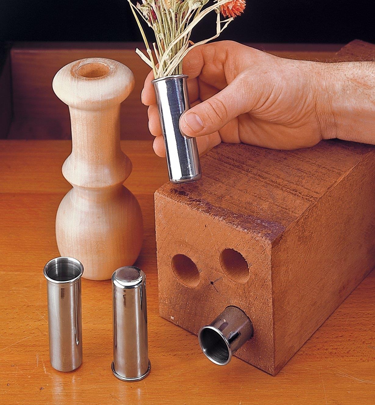 Stainless-Steel Inserts inserted into holes in a wooden block and in a candlestick