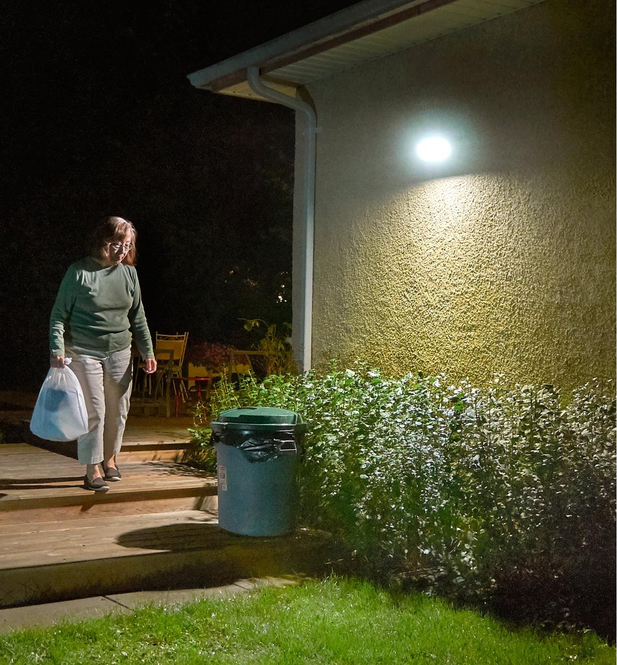 Motion-sensing solar LED floodlight activates as a figure approaches