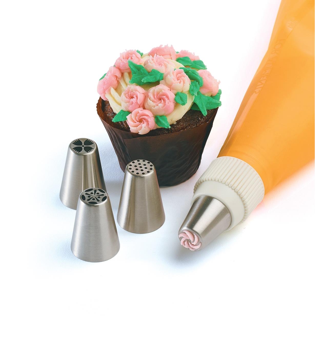 Set of 4 medium piping tips sitting next to a decorated cupcake, with one tip attached to a piping bag, sold separately