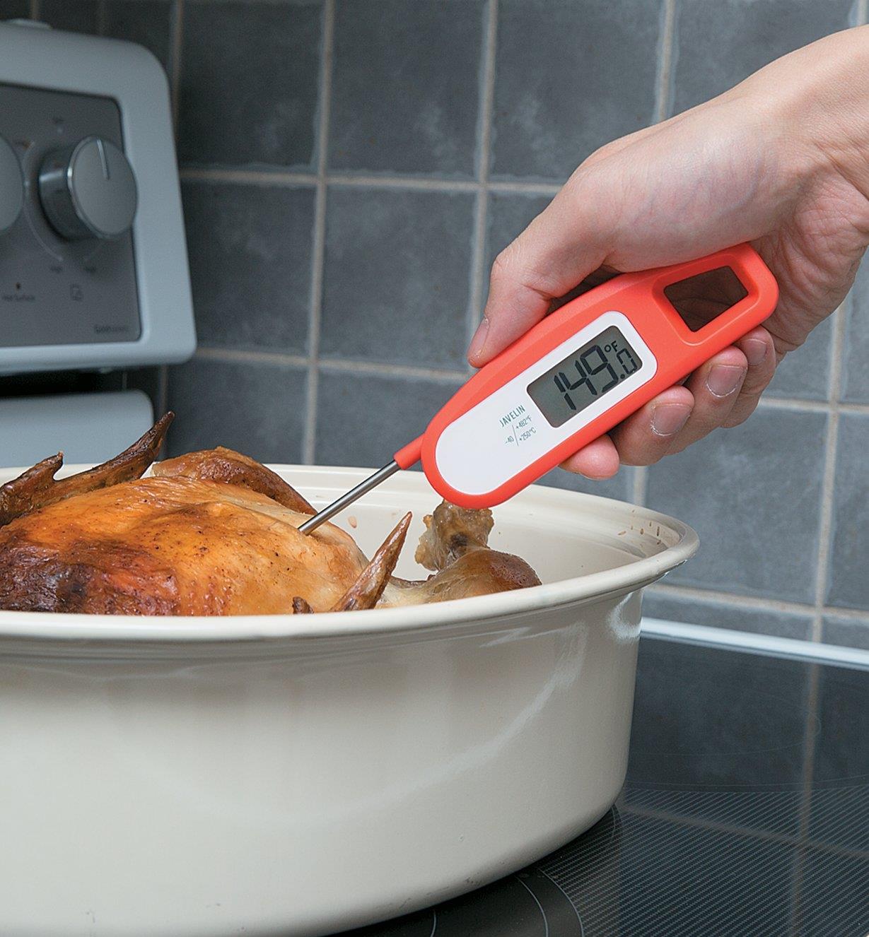 Personne insérant un thermomètre à mesure instantanée Javelin dans un poulet cuit dans un plat de cuisson
