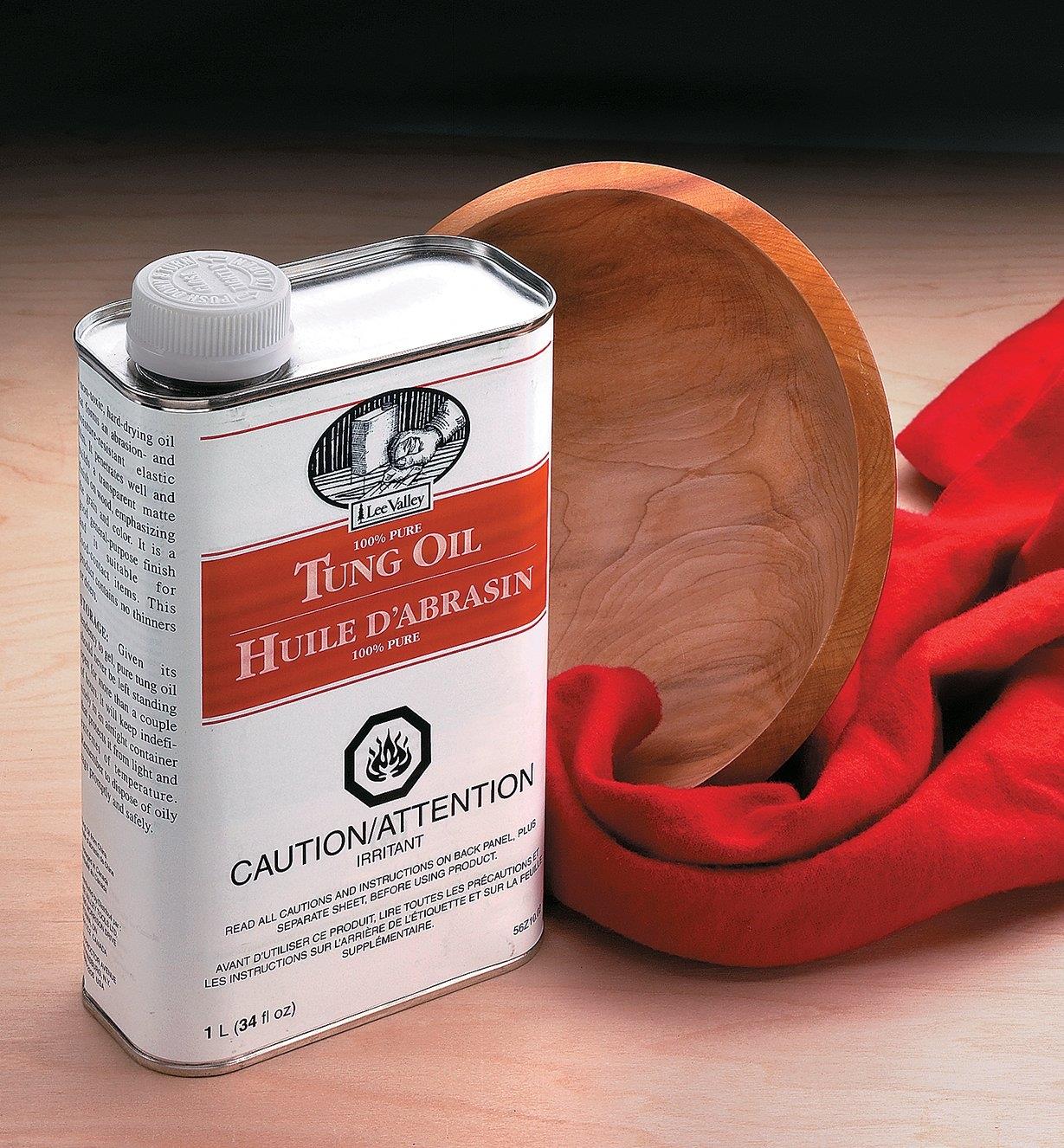 Can of tung oil next to a wooden bowl and a towel