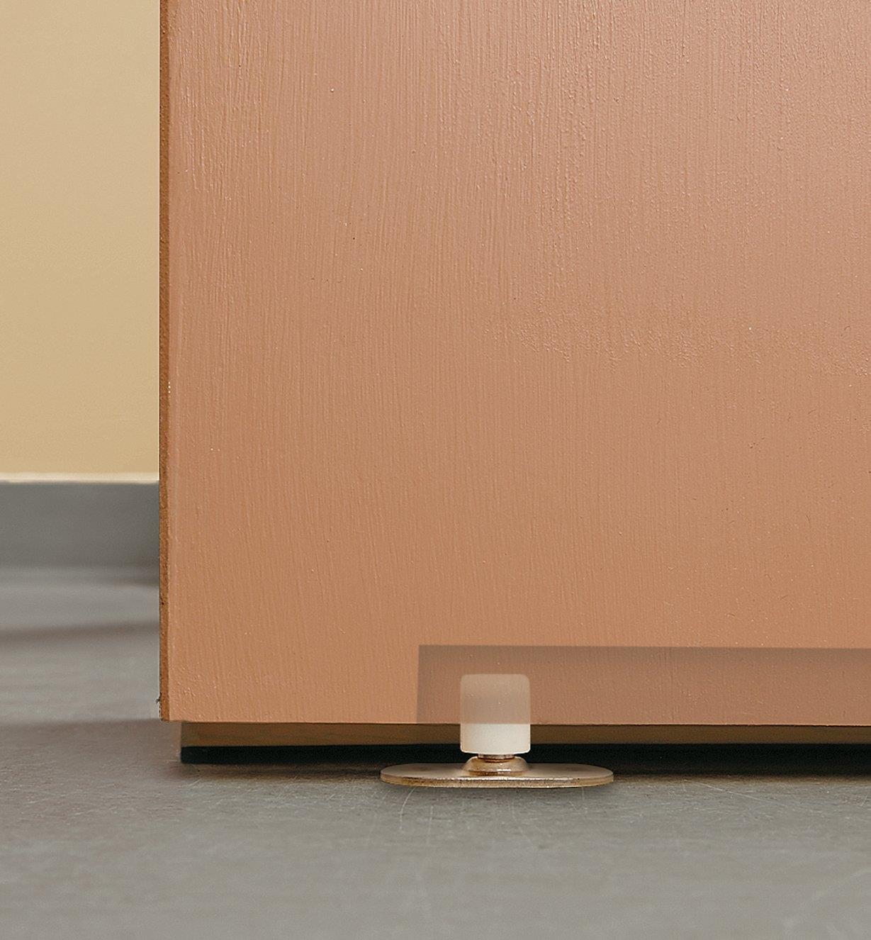 Ghosted view of floor-mounted guide roller installed in a door