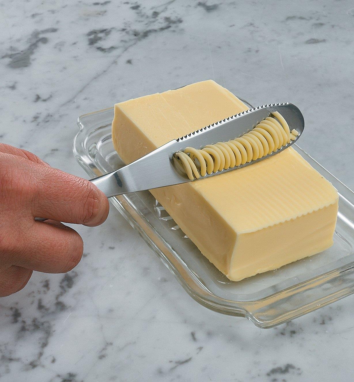 Drawing the knife across a block of butter, creating thin ribbons