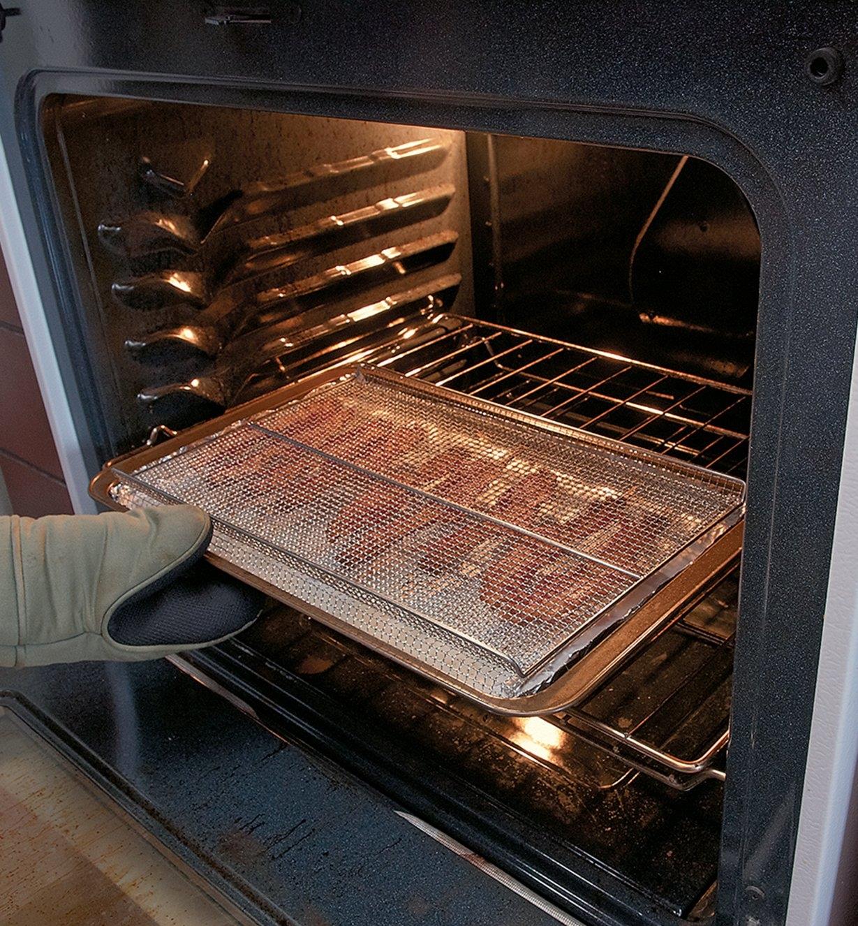 Personne cuisant du bacon au four avec une grille de refroidissement