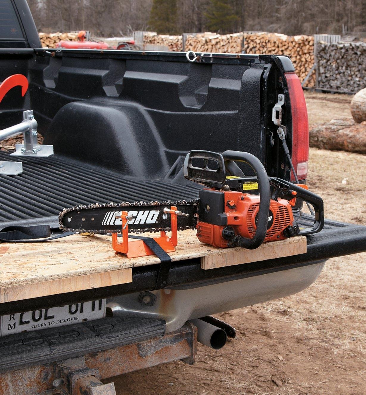 Vise clamped onto a chain-saw blade and tied to a truck tailgate with the included strap