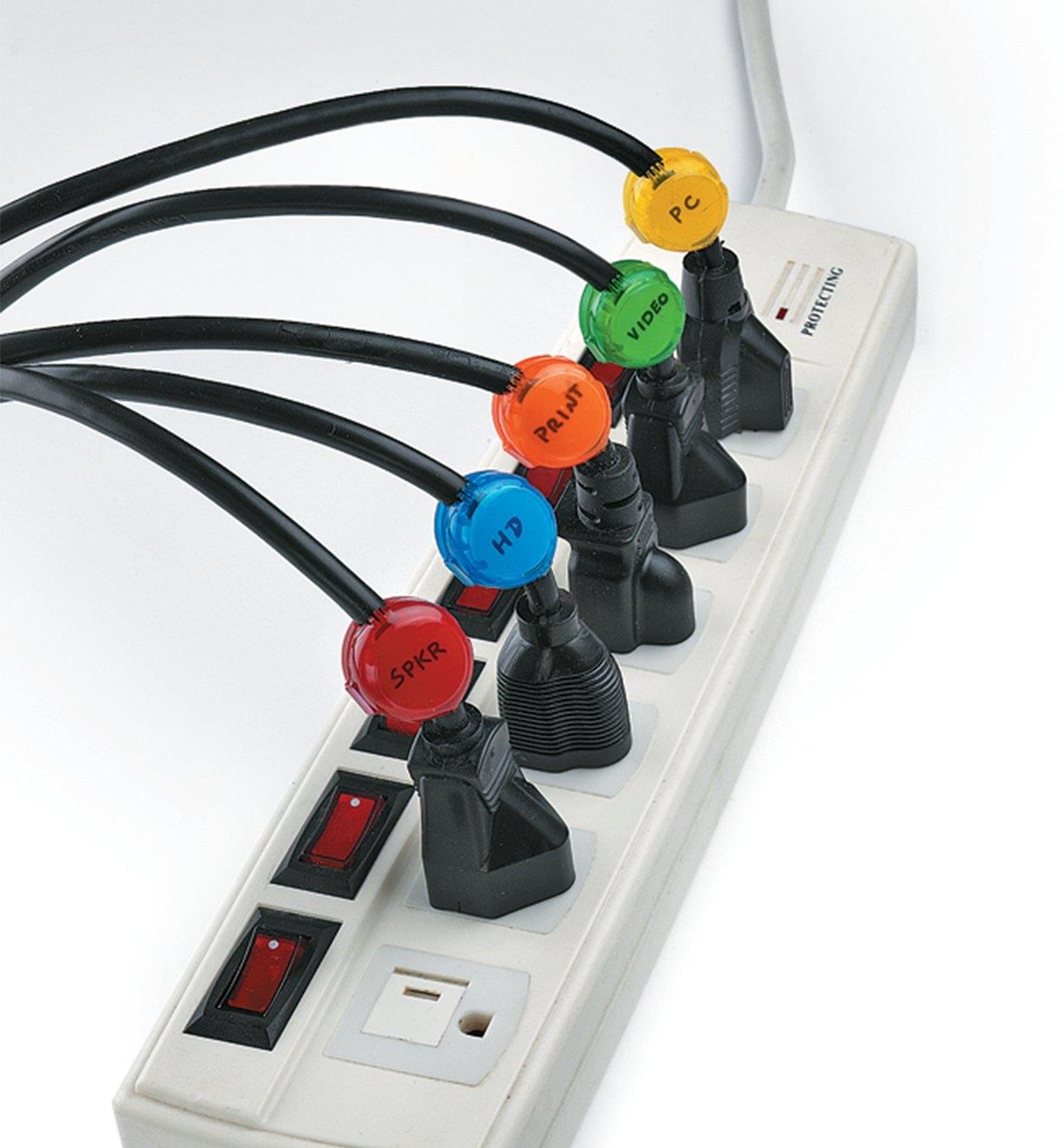 A power bar with five cords plugged in, each with a different-colored cord identifier attached