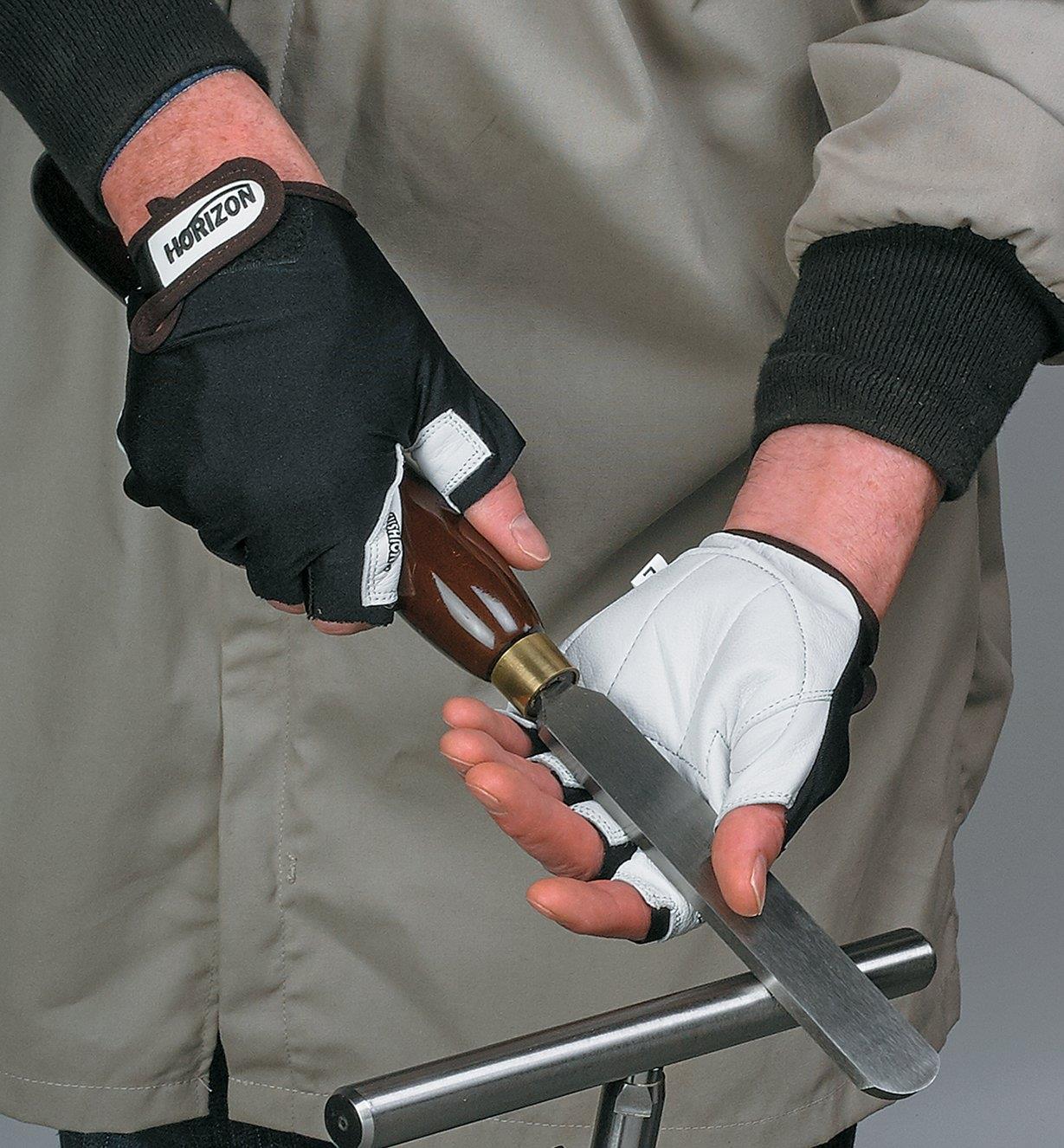A person wearing Anti-Vibration Gloves holds a turning scraper on a tool rest
