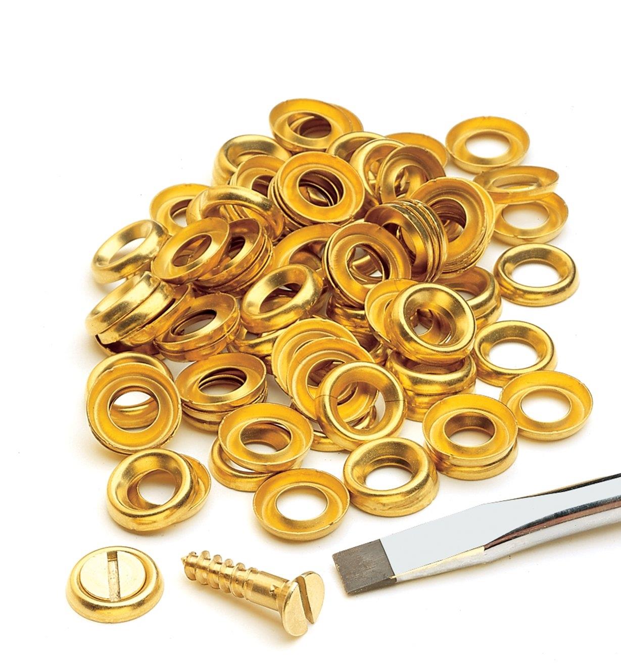 A pile of Brass Finishing/Cup Washers displayed with a screw and a screwdriver