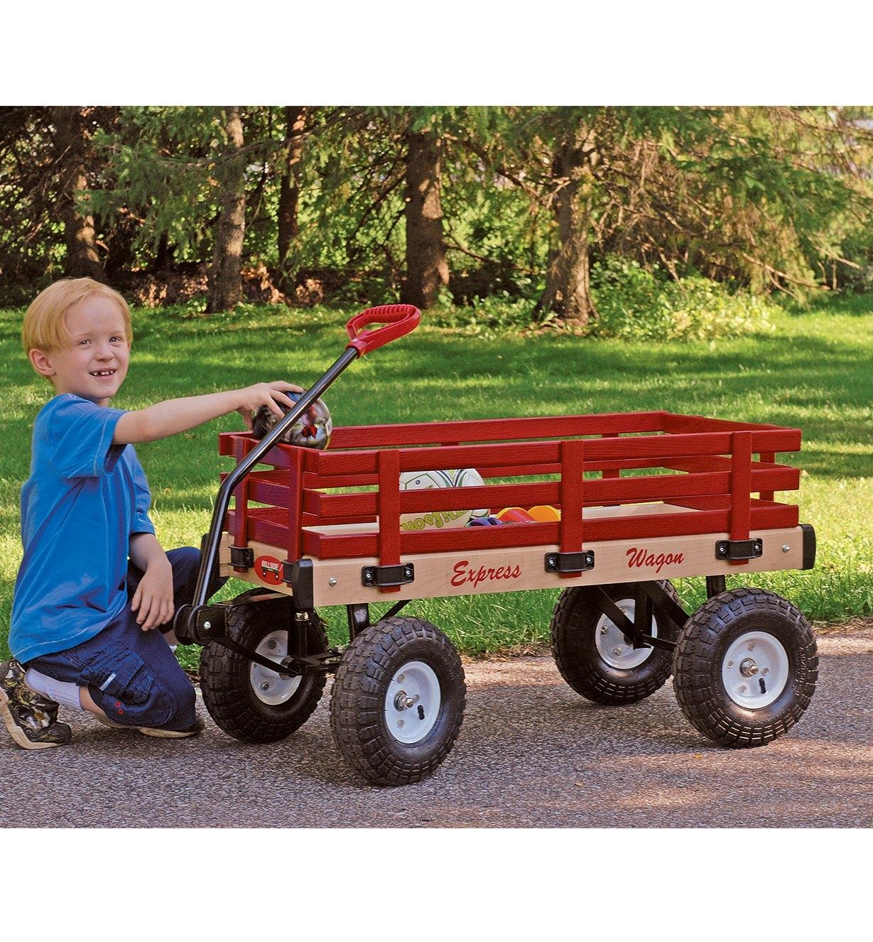 Garçon plaçant un ballon dans un chariot convertible toutes-saisons monté sur roues