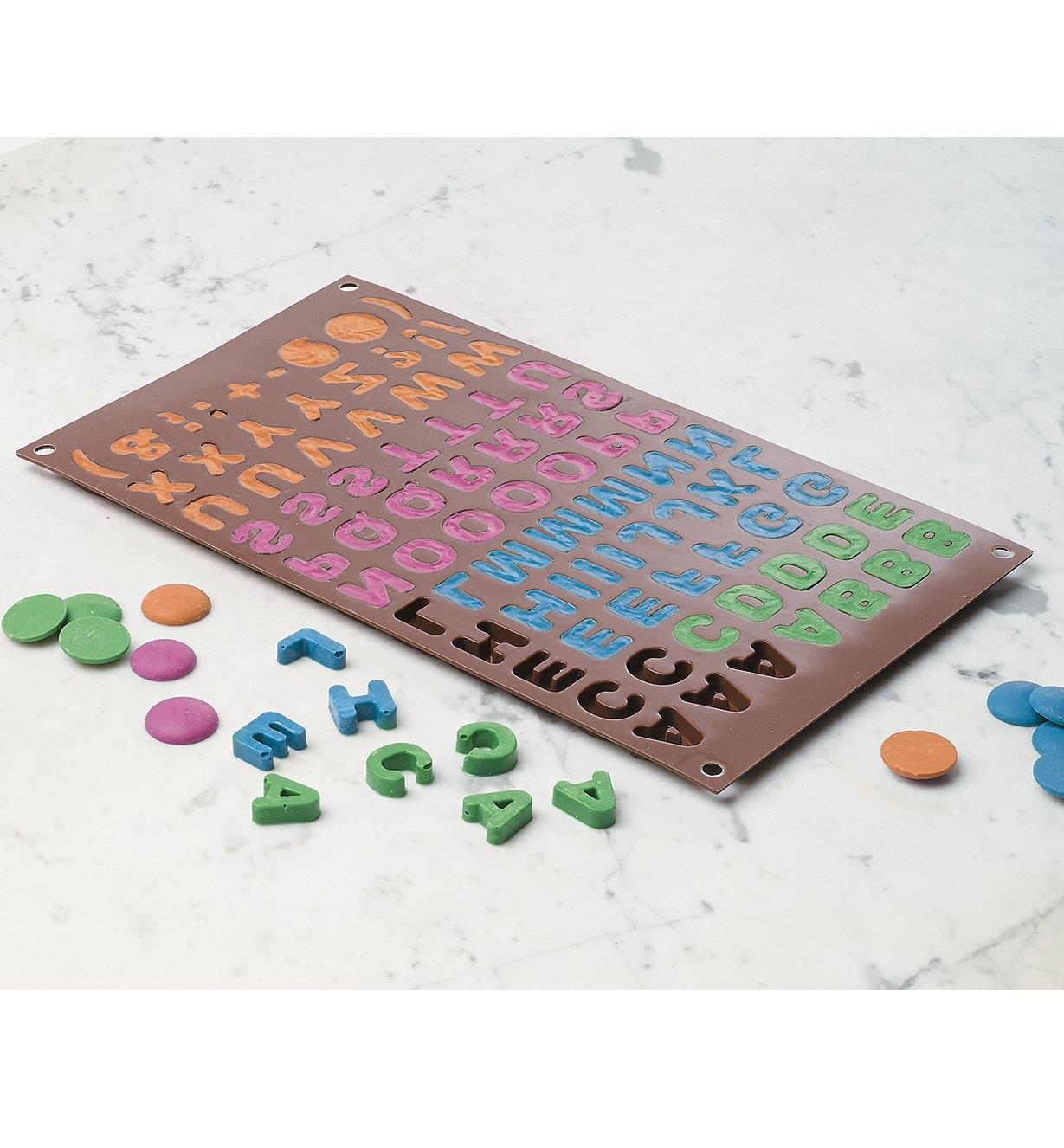 Chocolate Mold filled with various colors of chocolate, with some chocolate letters removed