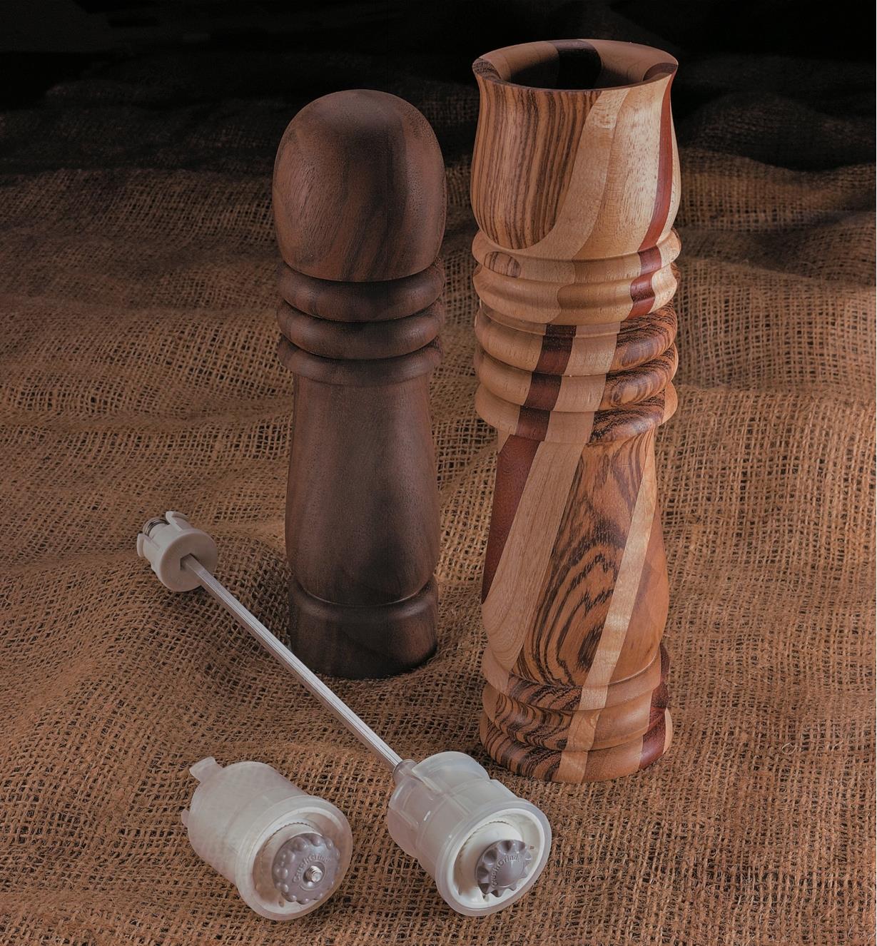 Ceramic Pepper Mill Mechanisms lying next to two completed wooden peppermills