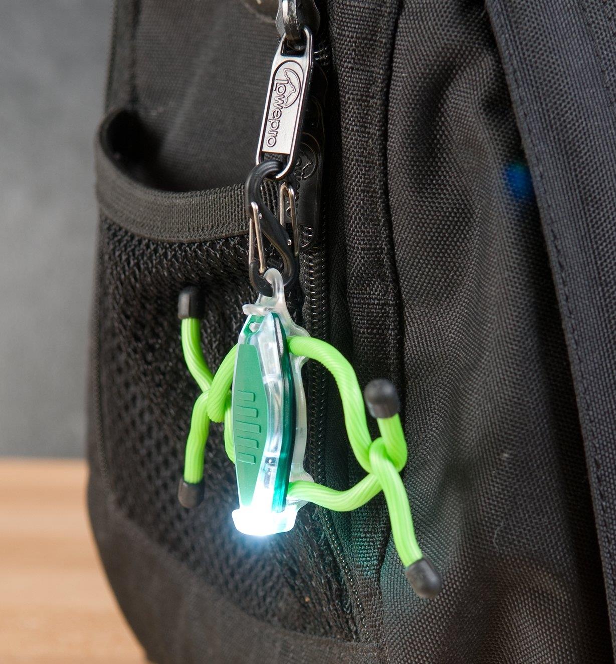 A Green BugLit LED Micro-Light attached to a backpack zipper pull
