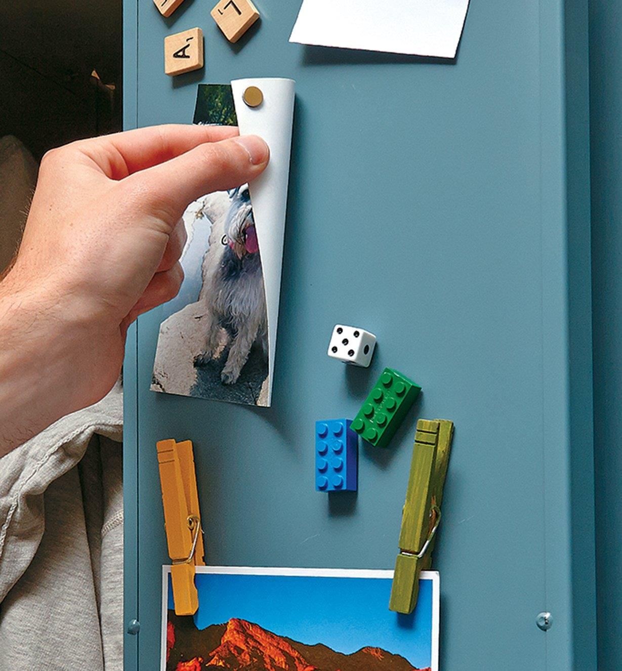 Hanging pictures and small items on a locker door using adhesive-backed magnets
