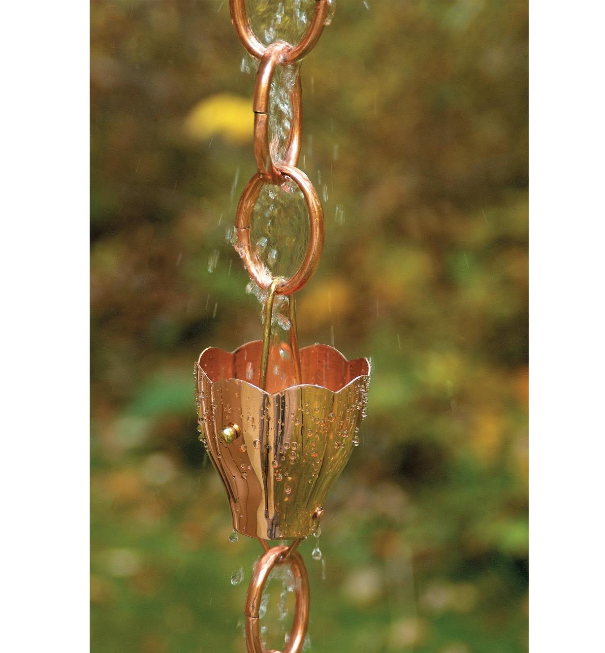 Water cascades through one of the fluted crocus-shaped funnels on the copper rain chain