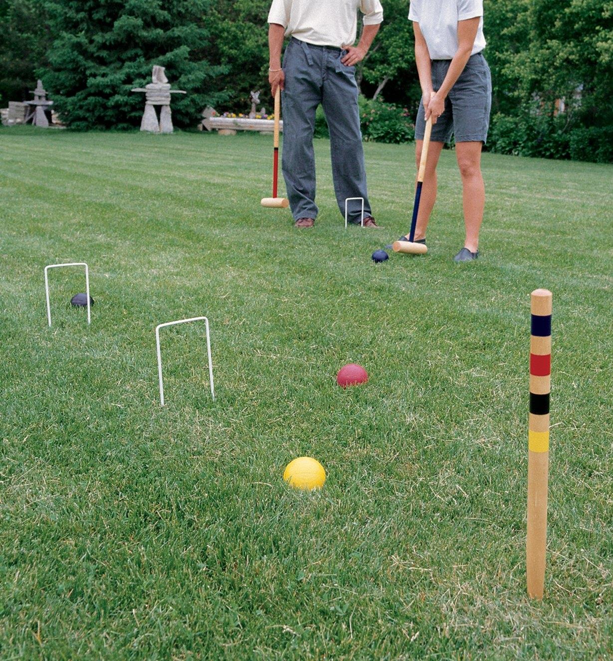 A man and woman playing croquet on grass
