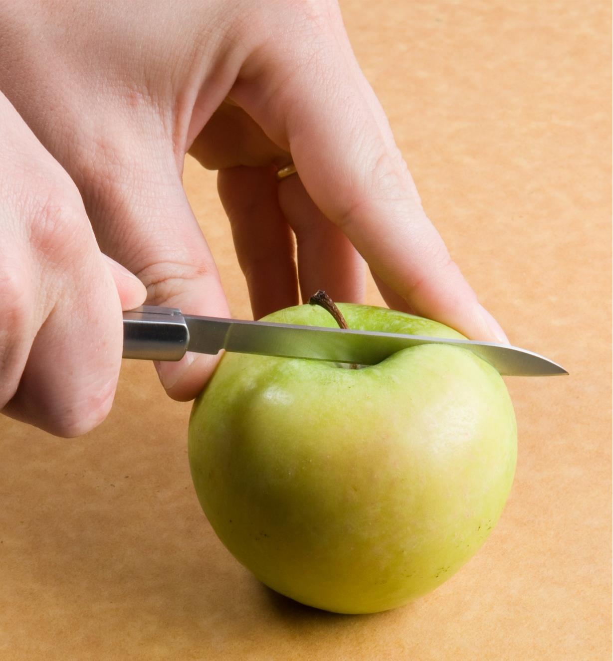 Personne coupant une pomme avec un couteau à fruits pliant