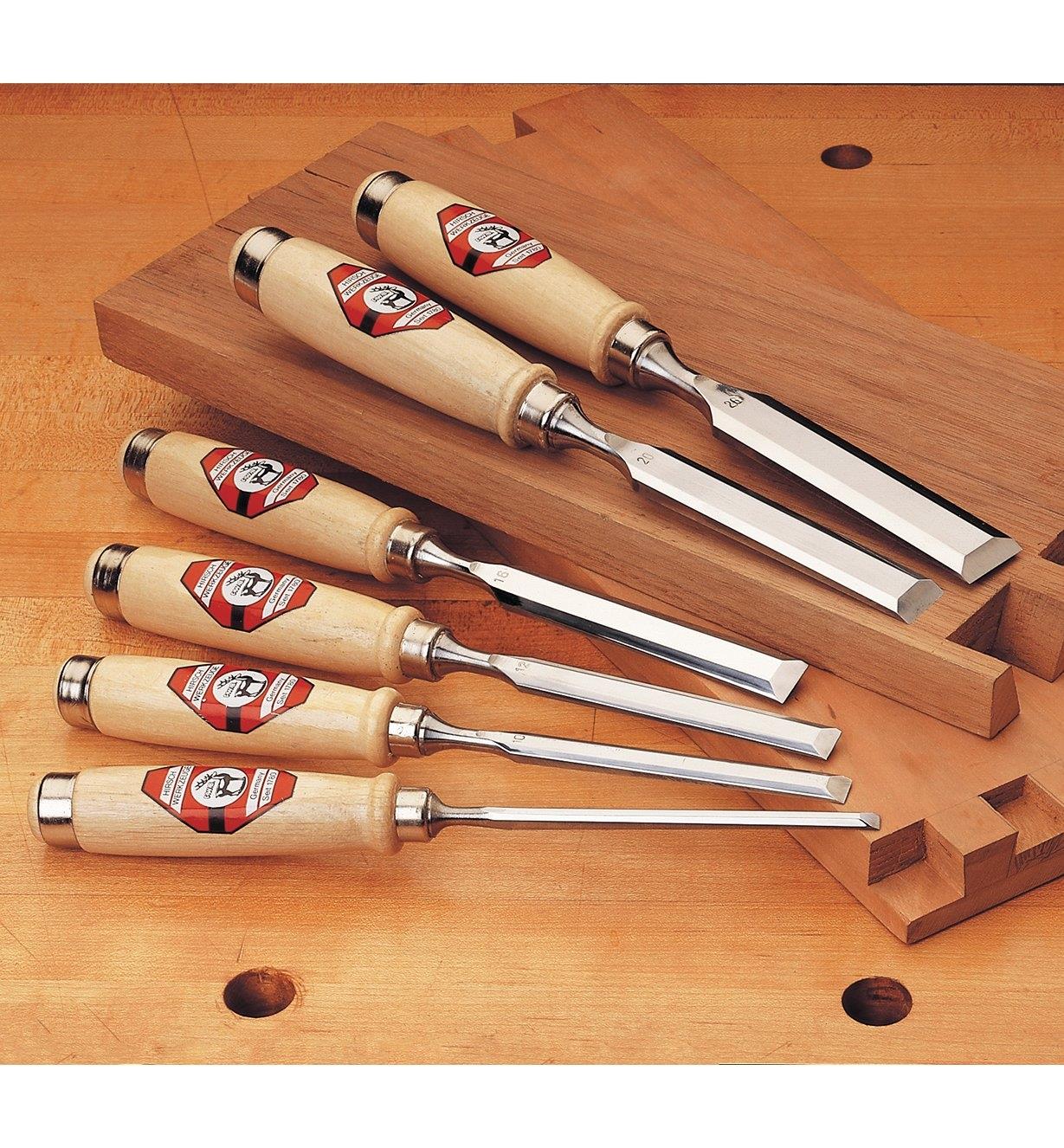 Hirsch Firmer Chisels lying on a workbench with boards cut with dovetail joints