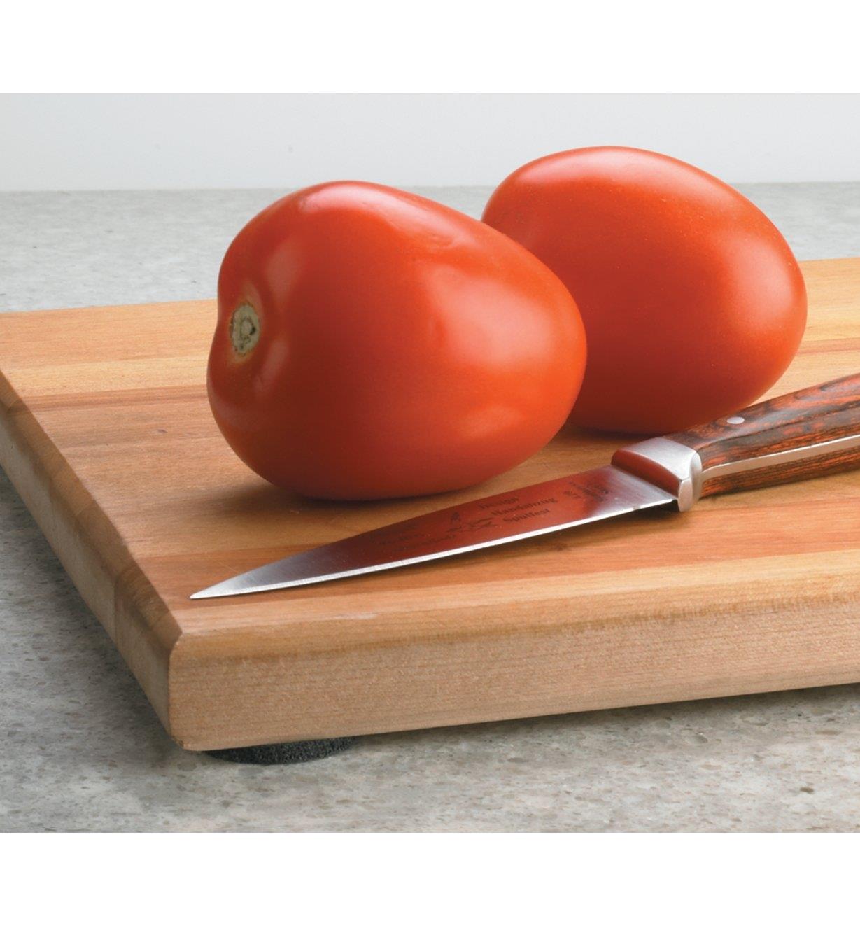 High-Friction Grip Discs applied to the underside of a cutting board, with tomatoes and a knife on top