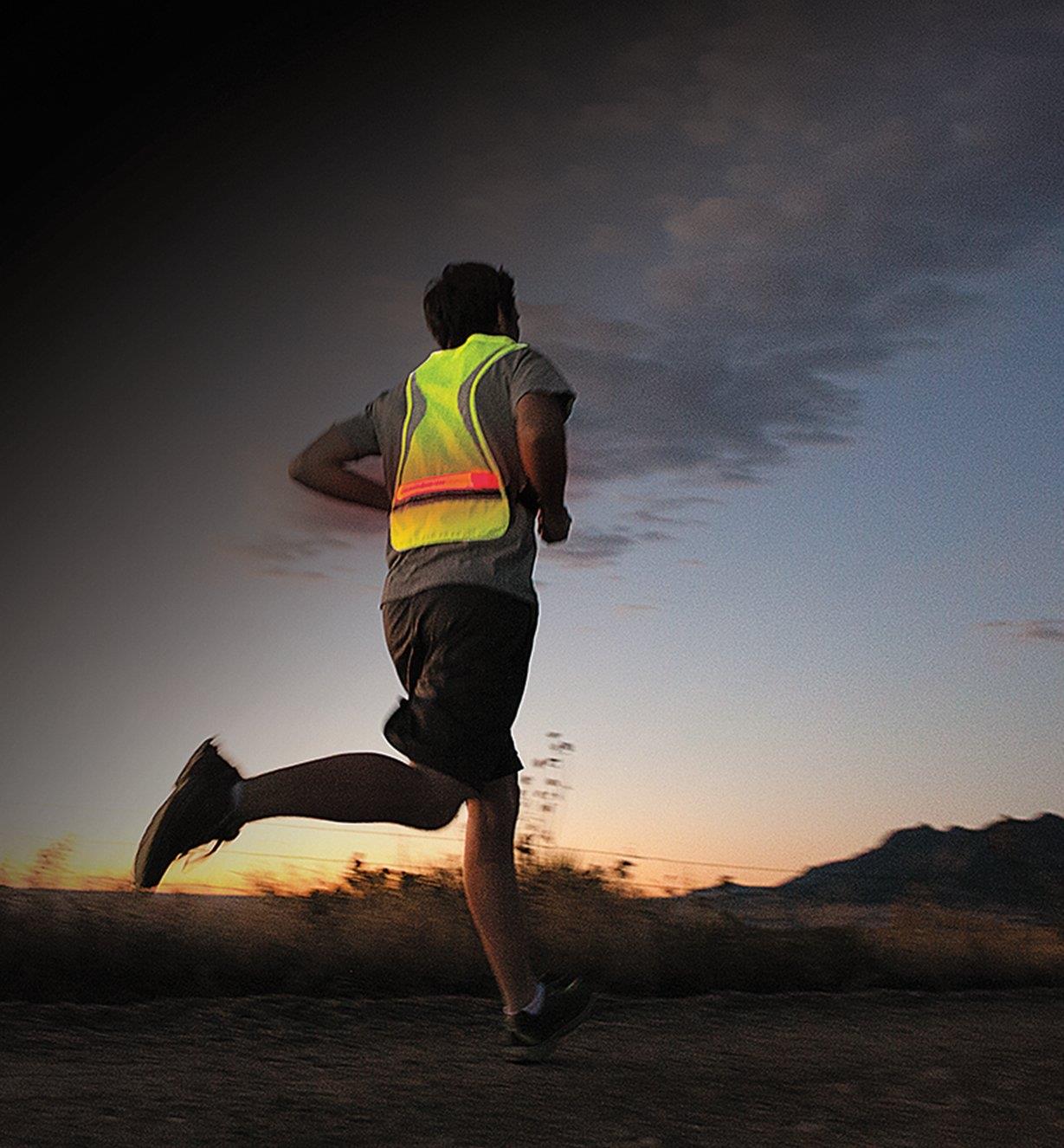 A man wearing the High-Visibility LED Vest running at dusk