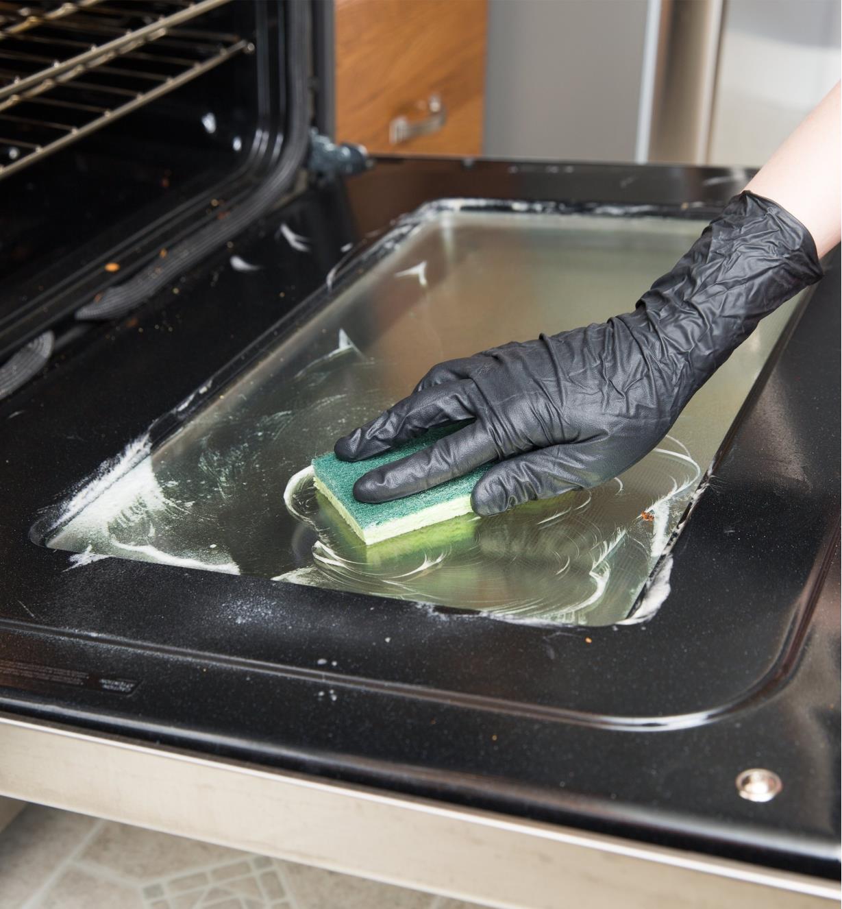 Wearing Grease Monkey Nitrile Gloves while cleaning an oven door