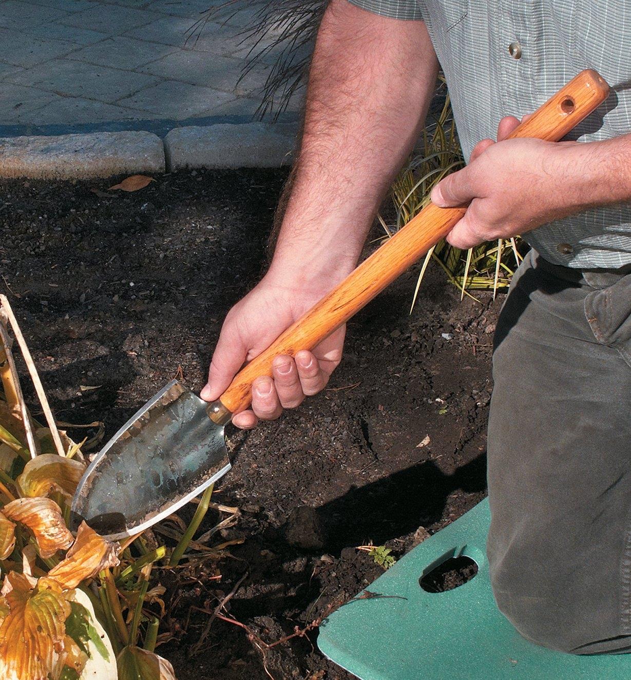 Digging in a garden with a long-handled trowel