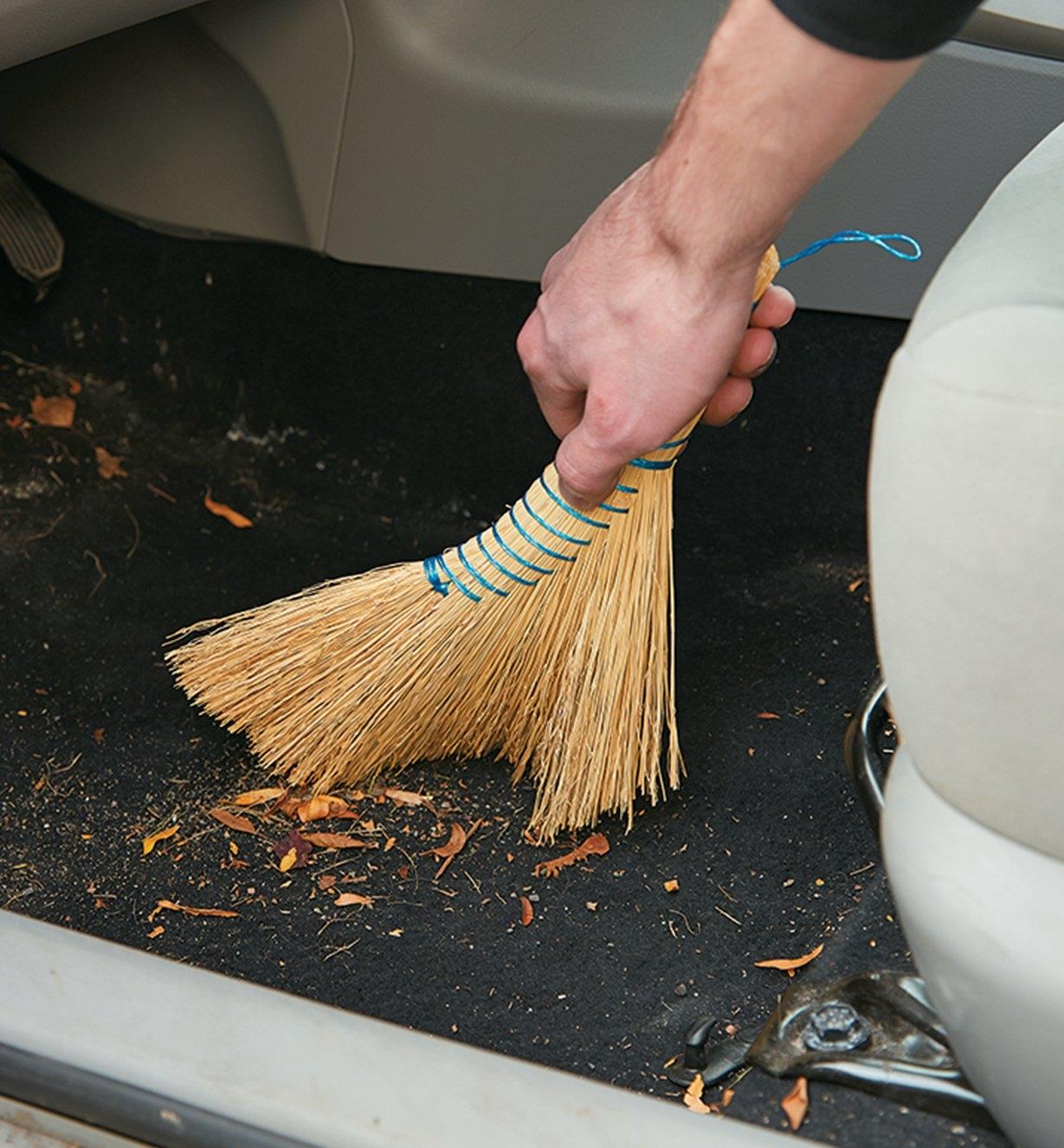 Using the Dutch Hand Broom to sweep out the floor of a car