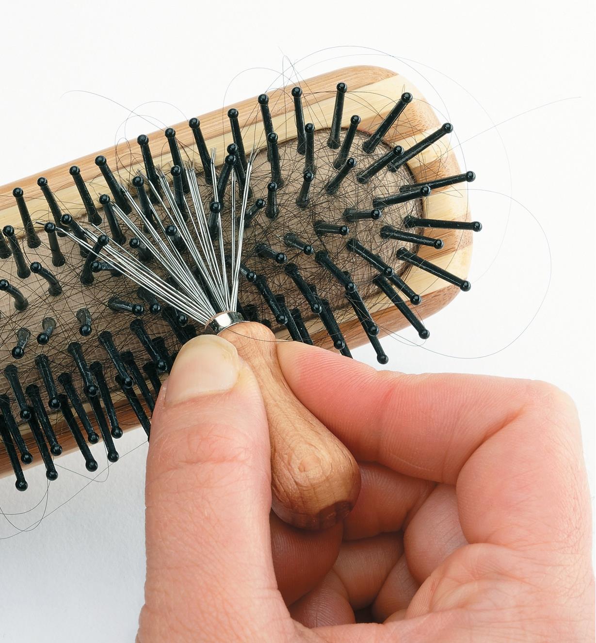Using the hairbrush-cleaning brush to clean between the bristles of a brush
