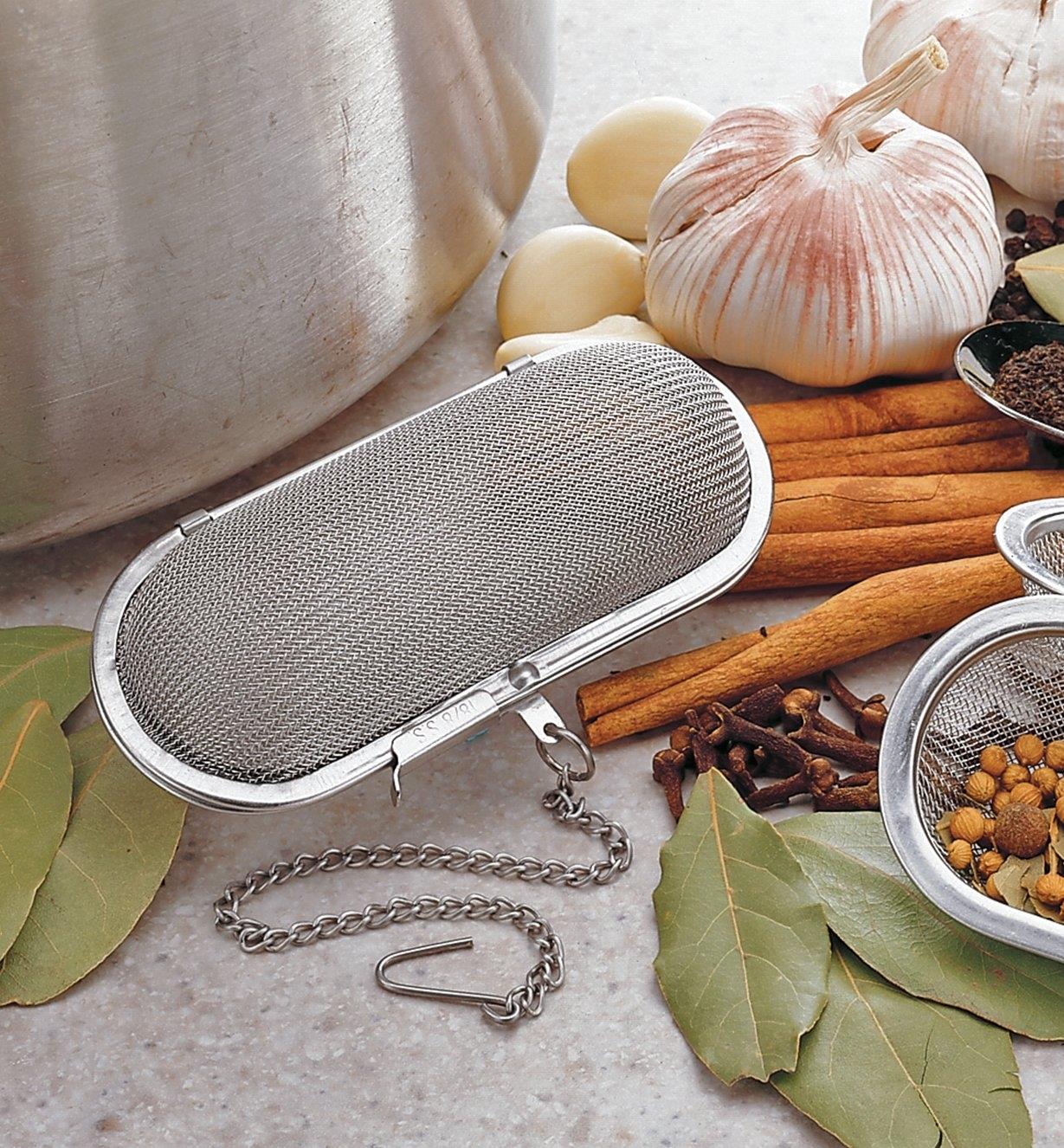 Herb & Spice Infuser on a counter beside a pot and among various herbs and spices