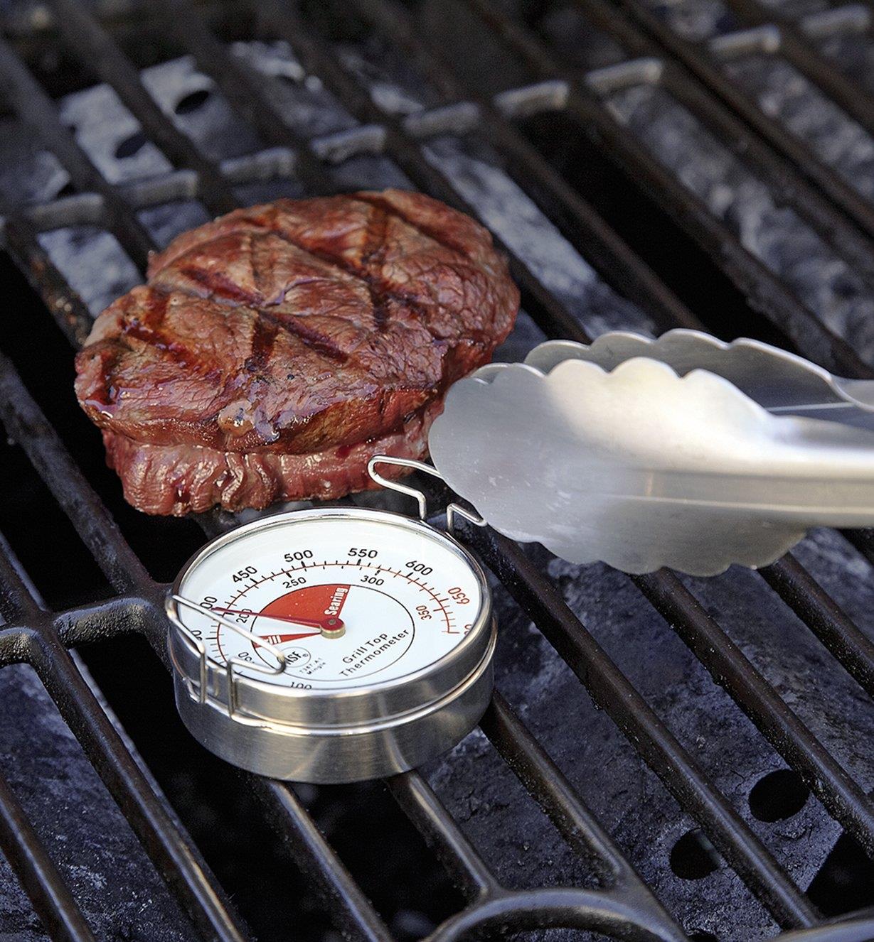 Thermomètre de surface près d'un steak sur une grille de barbecue