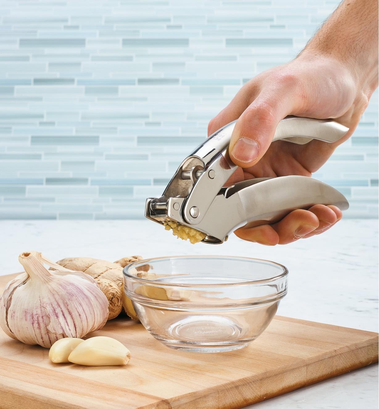 Using the garlic press to mince garlic into a bowl