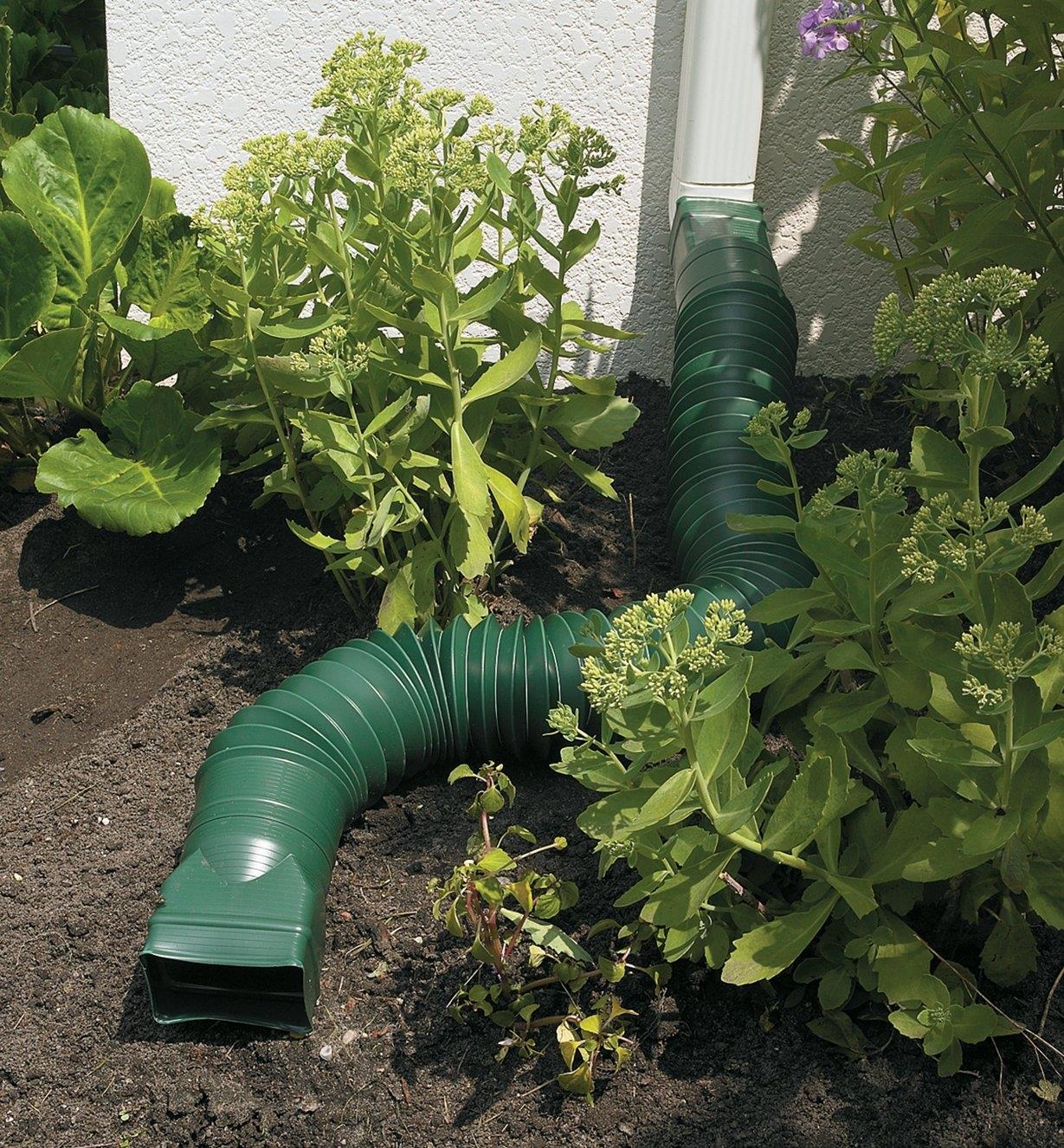 Green Downspout Diverter attached to a downspout, diverting water flow away from a garden