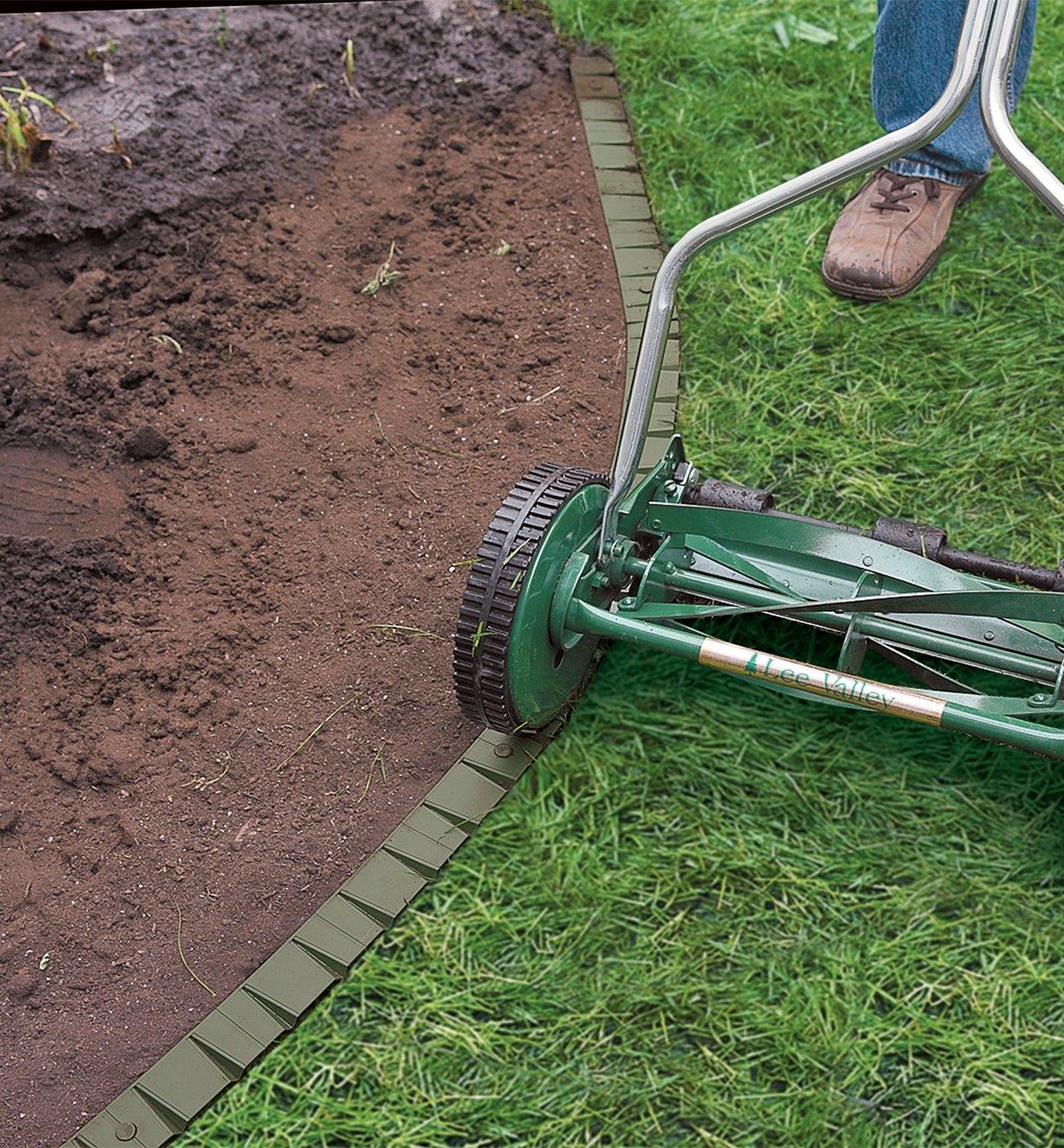 A reel mower rolls over installed Flexible Lawn Edging