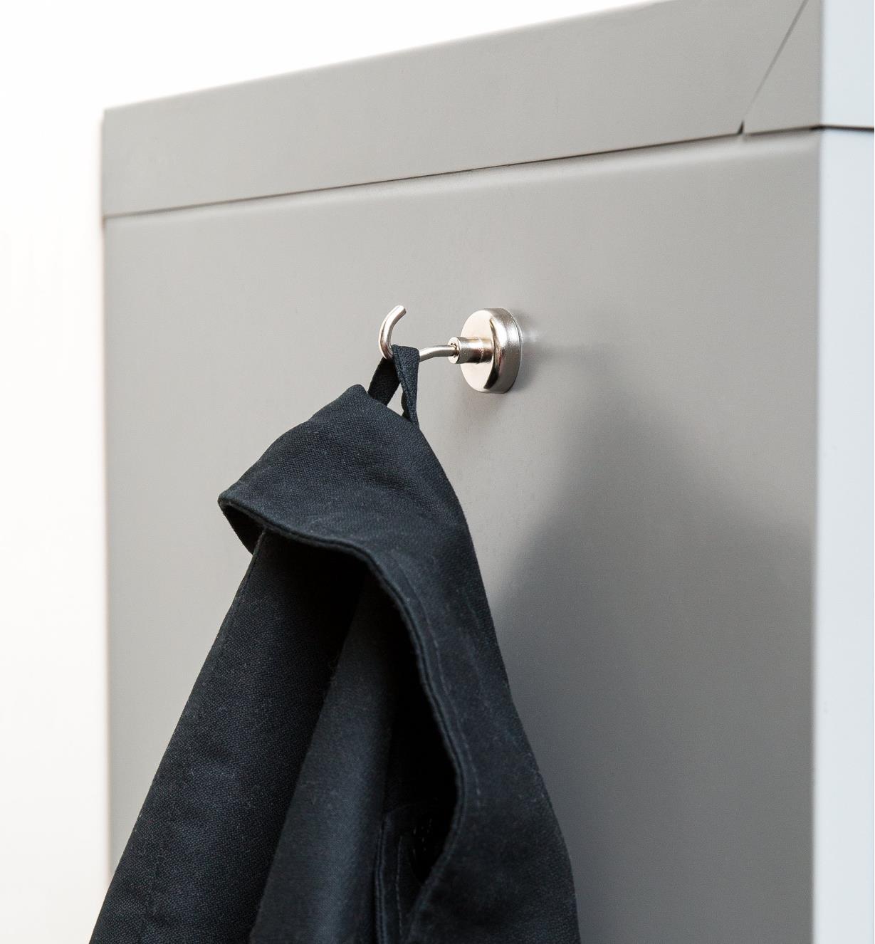 A jacket hanging on a magnet-mounted hook attached to a metal cabinet