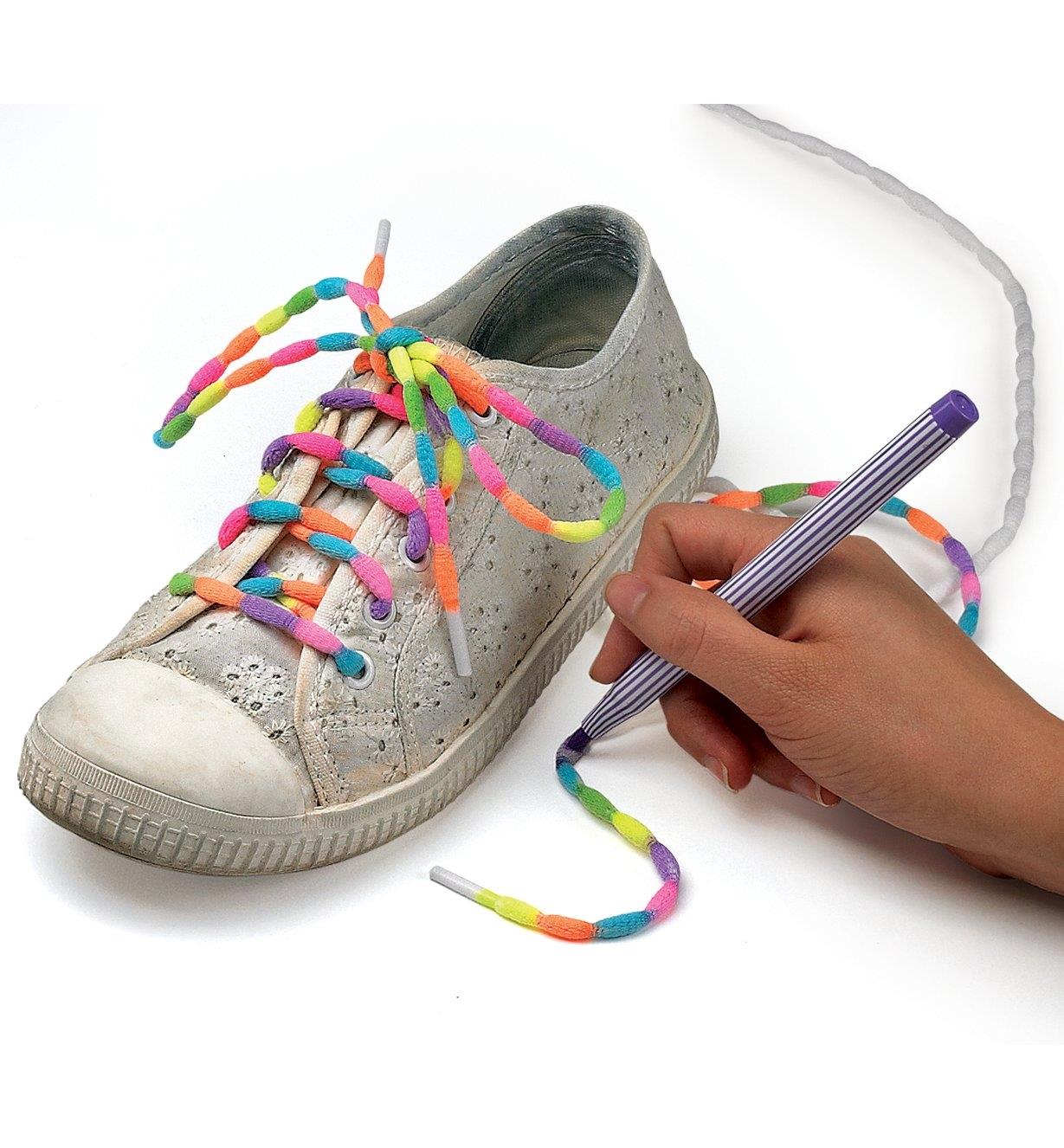 Coloring a lace with different colors of makers, beside a shoe with a lace already colored