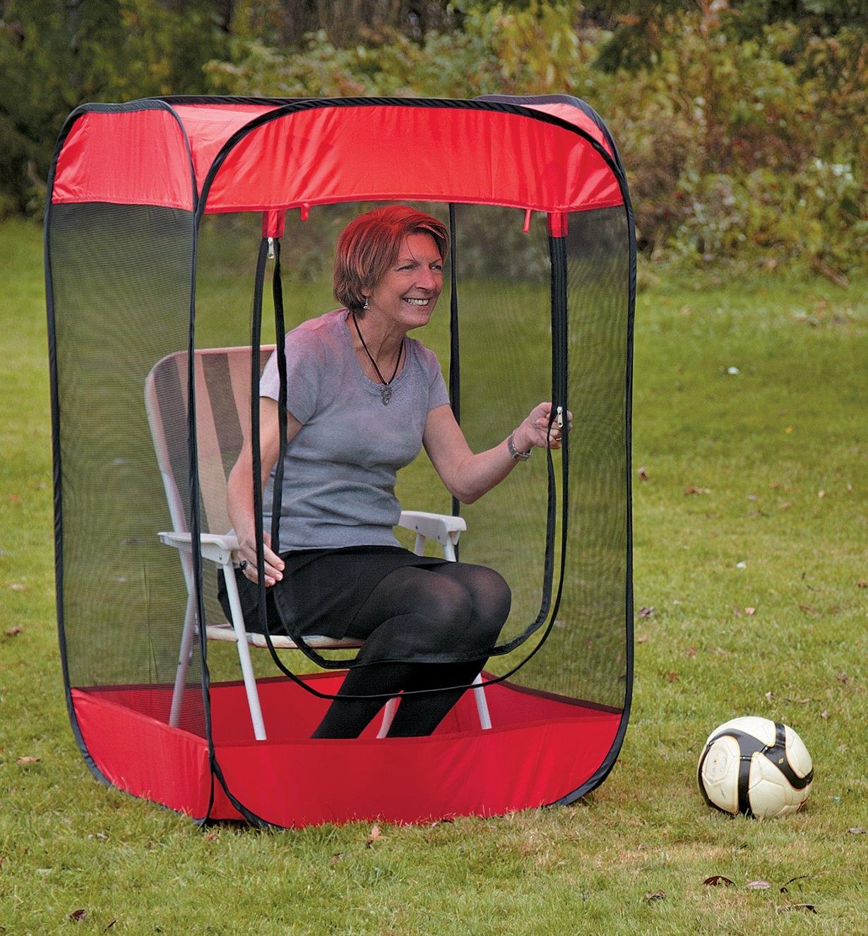 A woman sits in a lawn chair inside the Insect-a-Hide Pop-Up Shelter