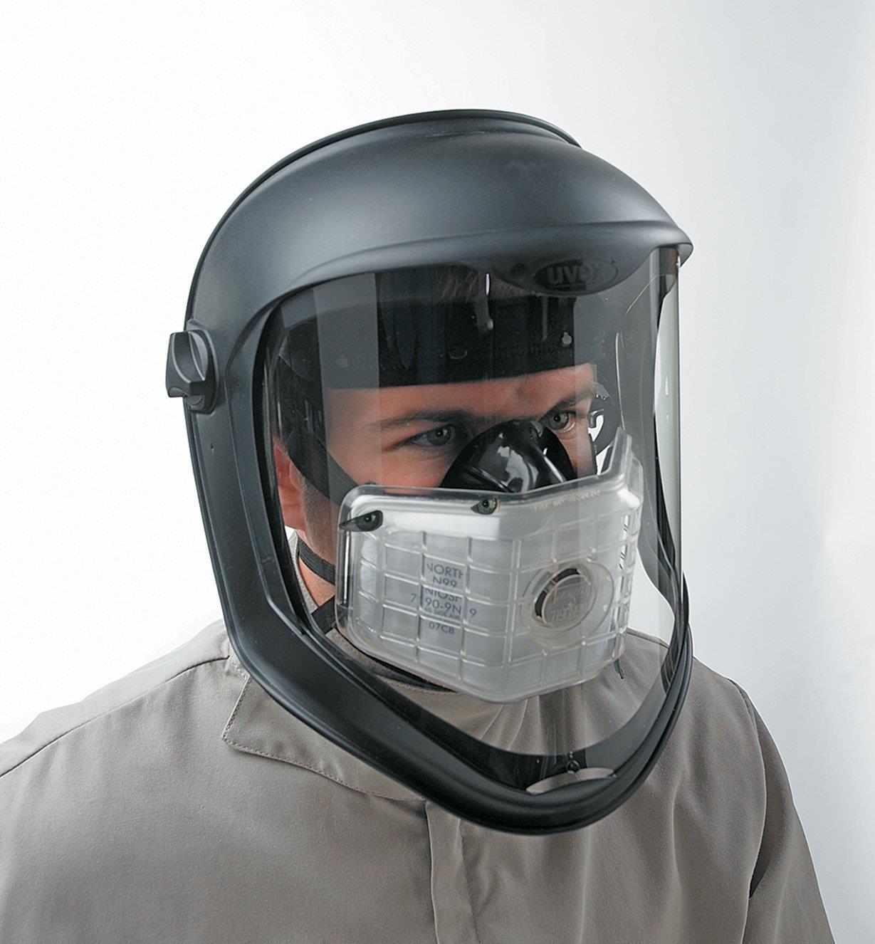 Man wearing a low-profile respirator under a face shield 