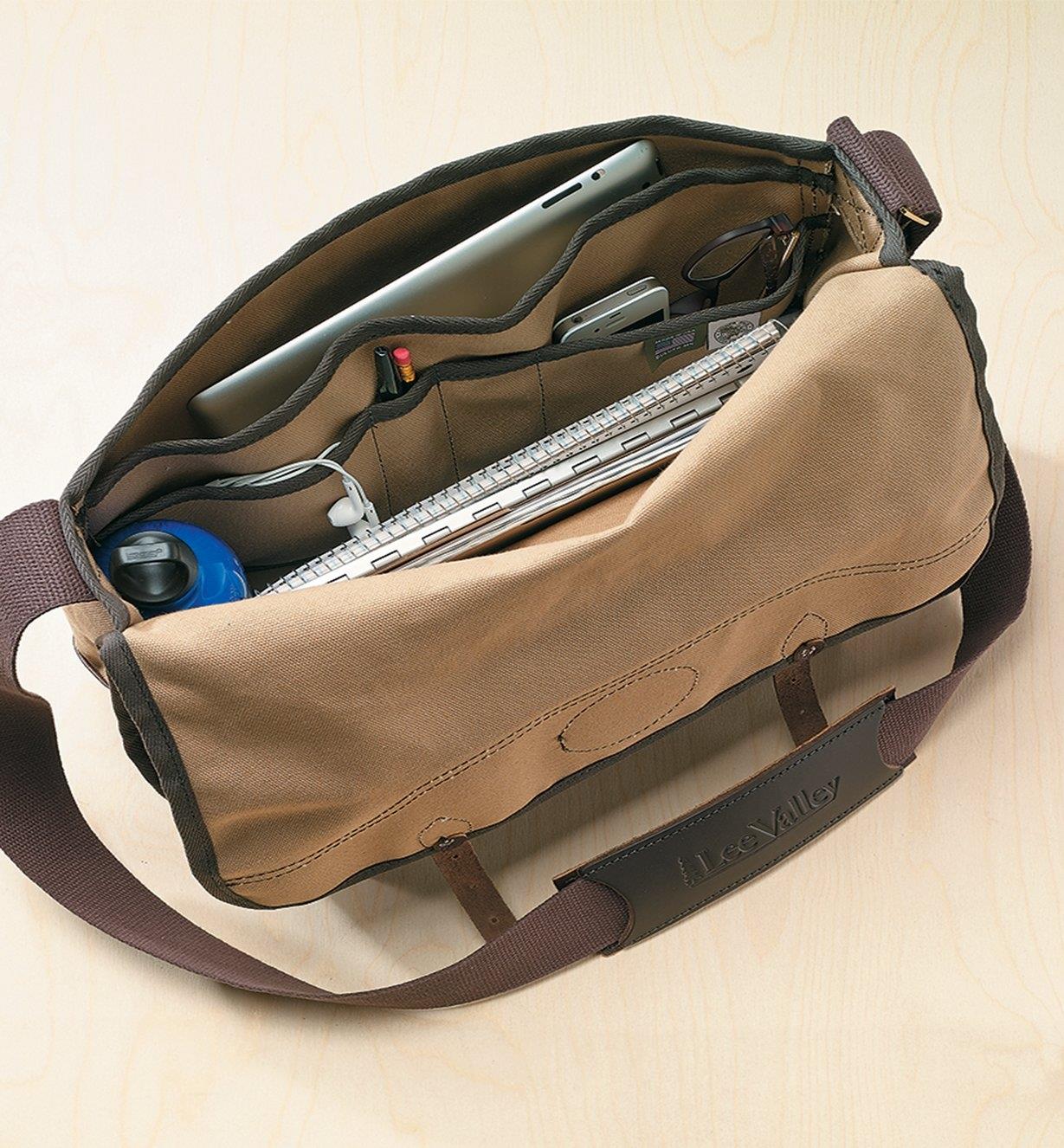 Lee Valley Shoulder Bag sitting open, with various pockets holding a laptop, a water bottle, pens, notebooks, a phone and glasses
