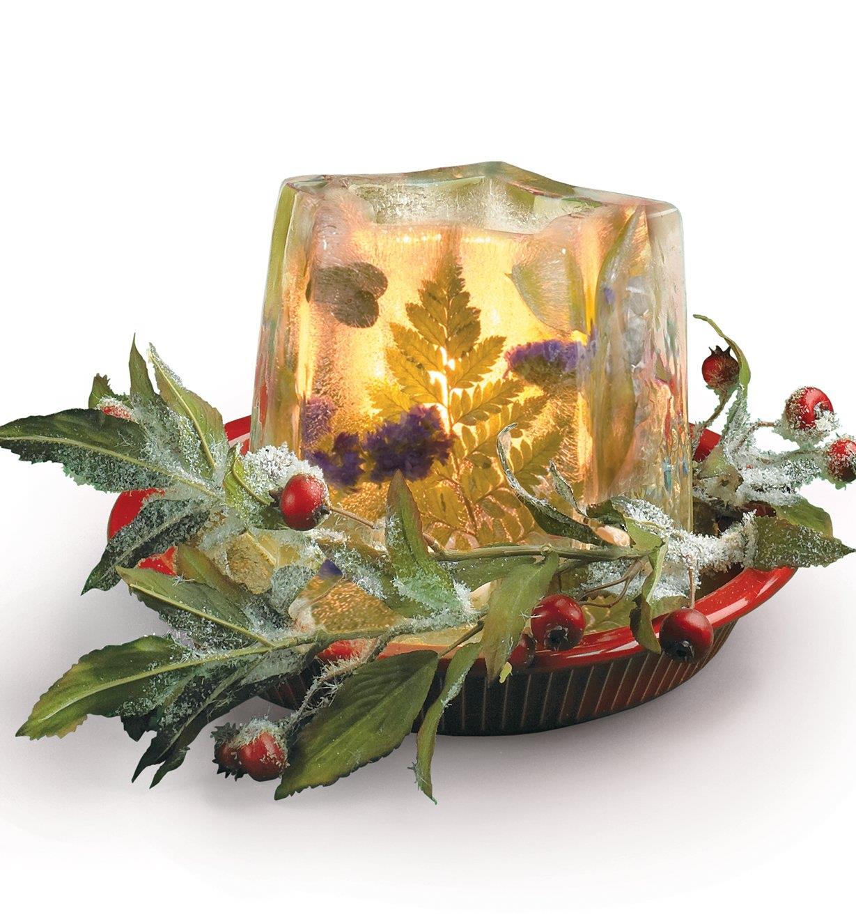 Lanterne de glace servant de centre de table avec des fleurs et des feuilles congelées à l’intérieur