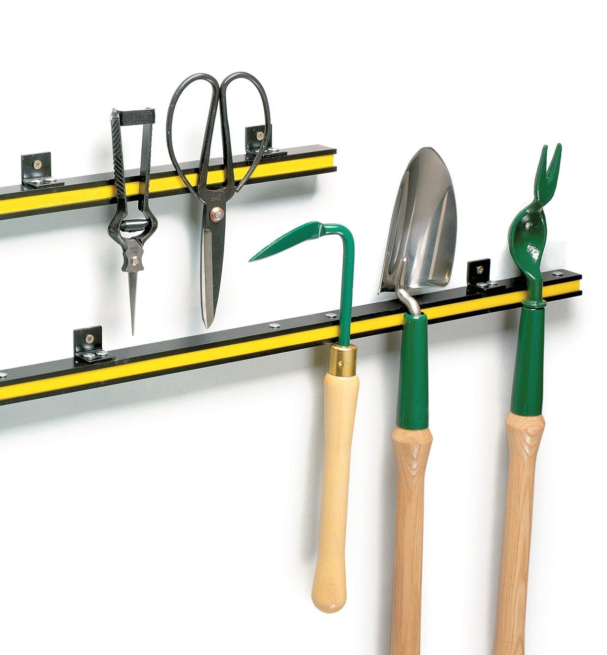 Both sizes of tool bar attached to a wall, with various garden tools clinging to them