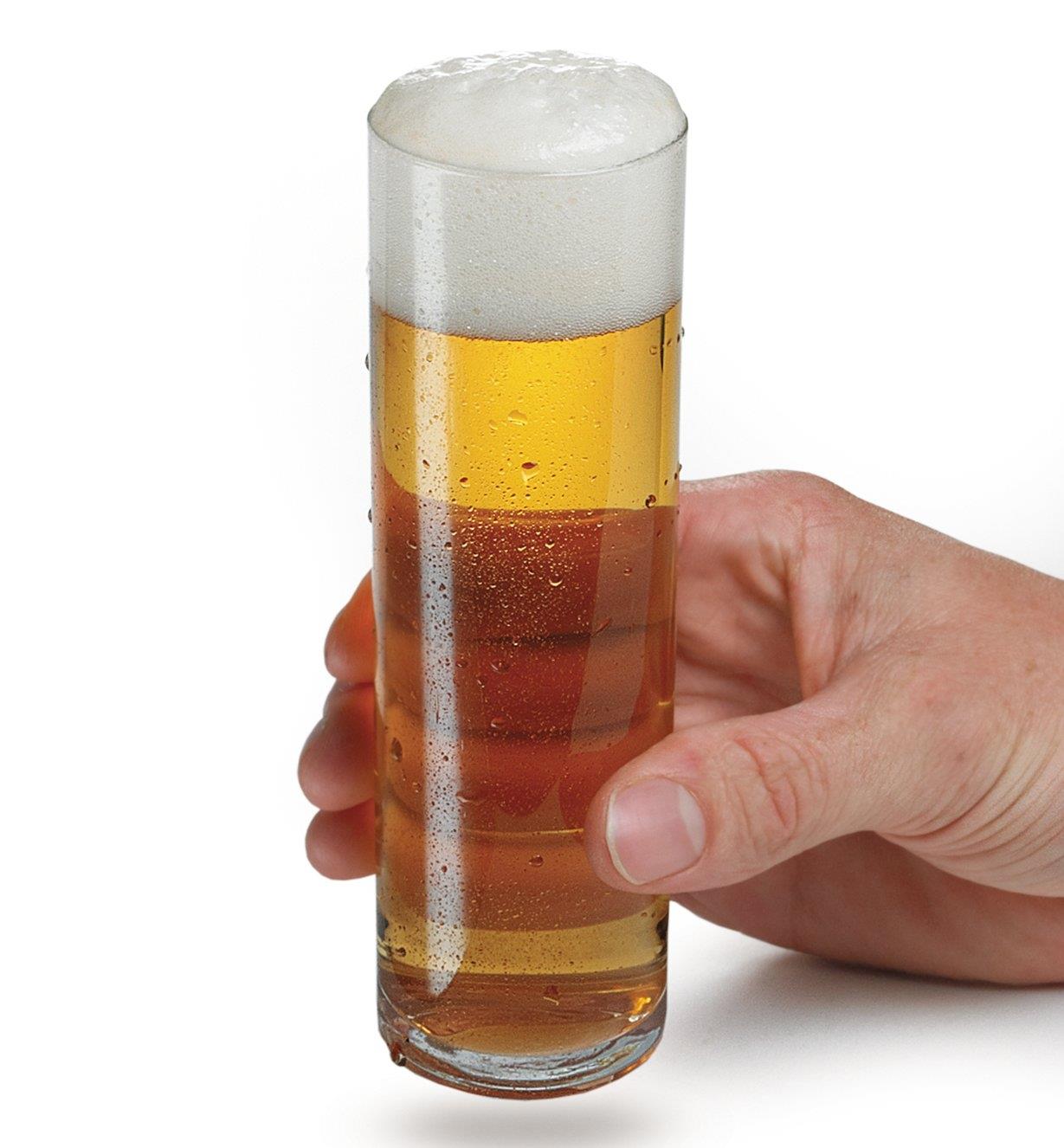 Personne tenant un des verres à bière Kölsch remplie de bière