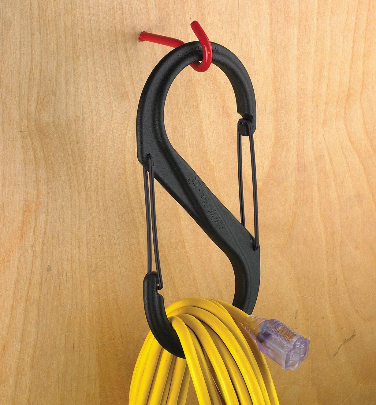 A coiled extension cord held in a 10 1/2" S-Biner hanging on a wall hook