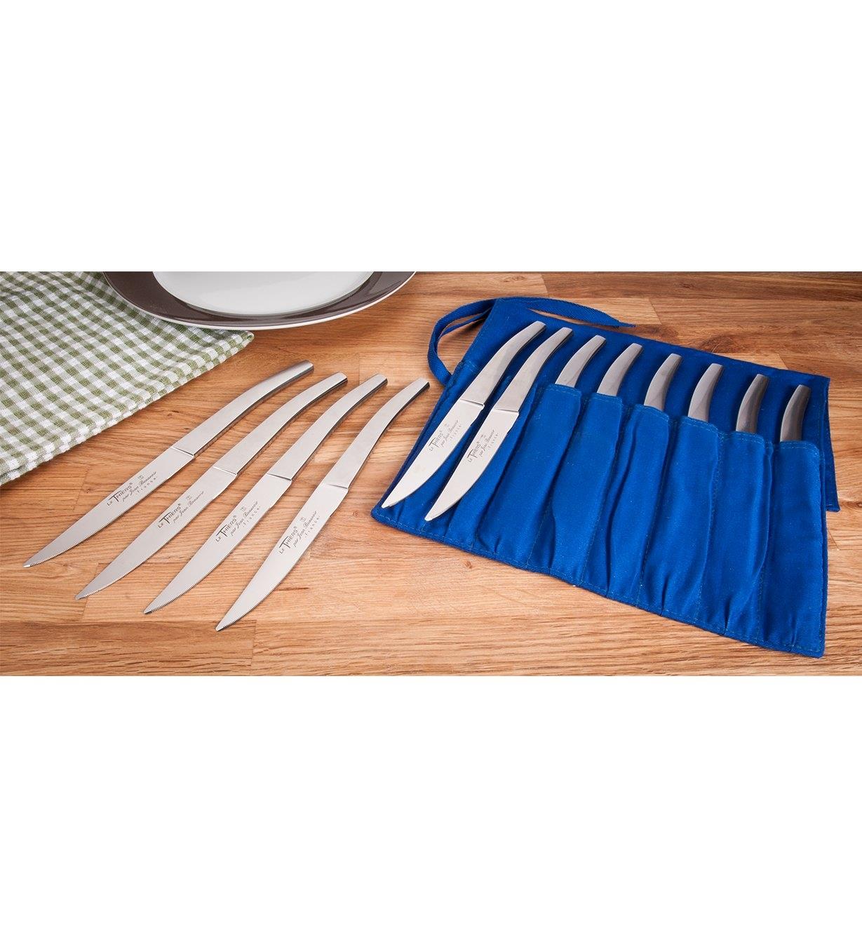 Set of eight bistro knives in roll beside set of four on dining table