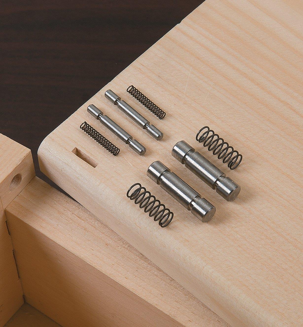 Both sizes of hinge pins and springs sitting on a box lid
