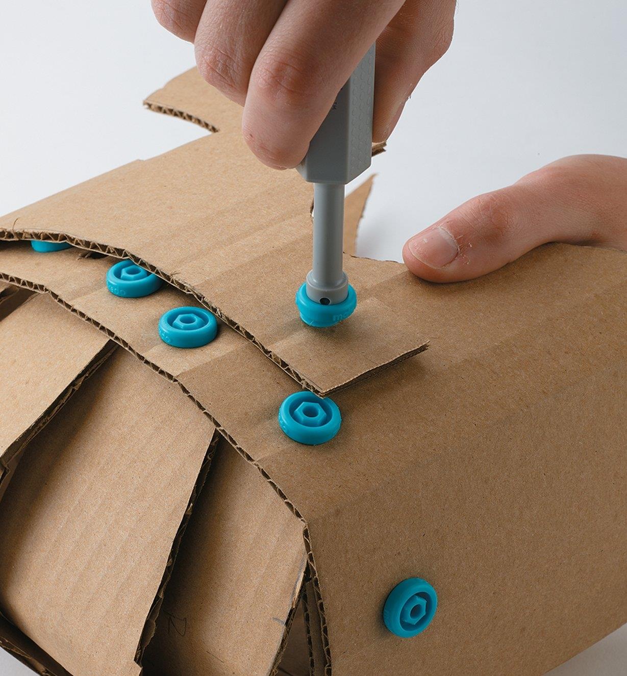 Fastening cardboard together using Makedo plastic screws and screwdriver