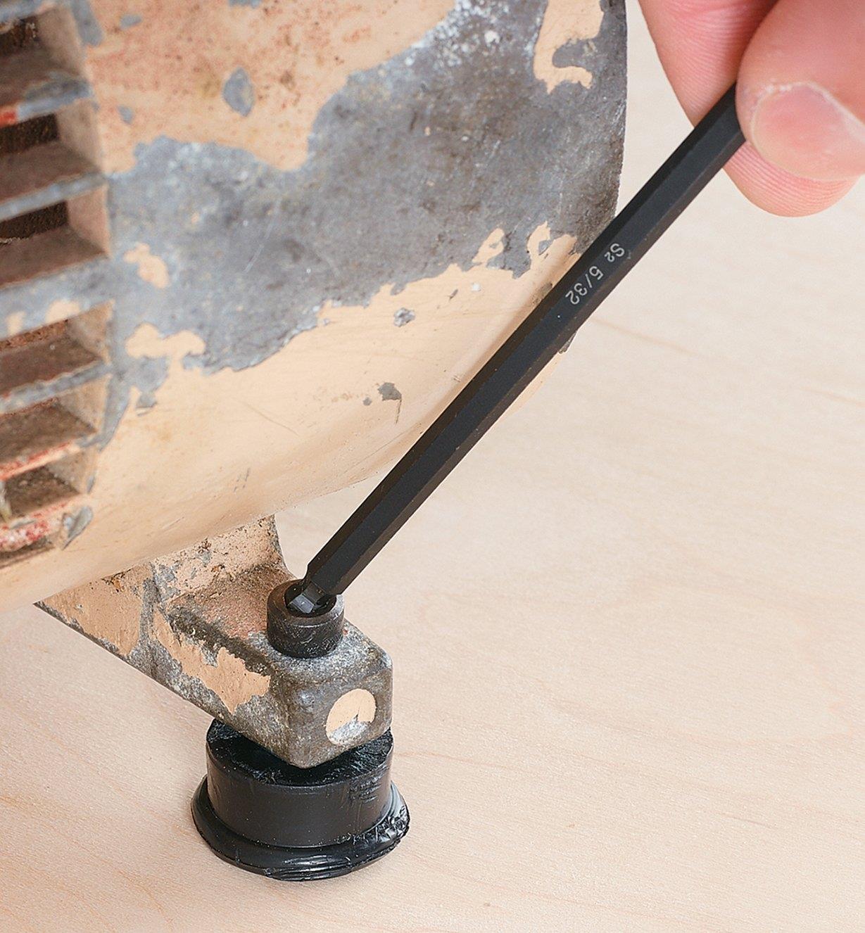 Using the ball end of a hex key to access a fastener on a machine foot