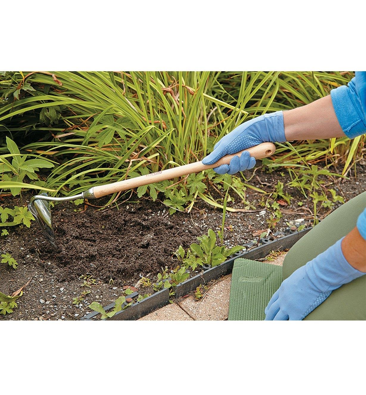 Digging in a flower garden using the Mid-Length Trenching Hoe